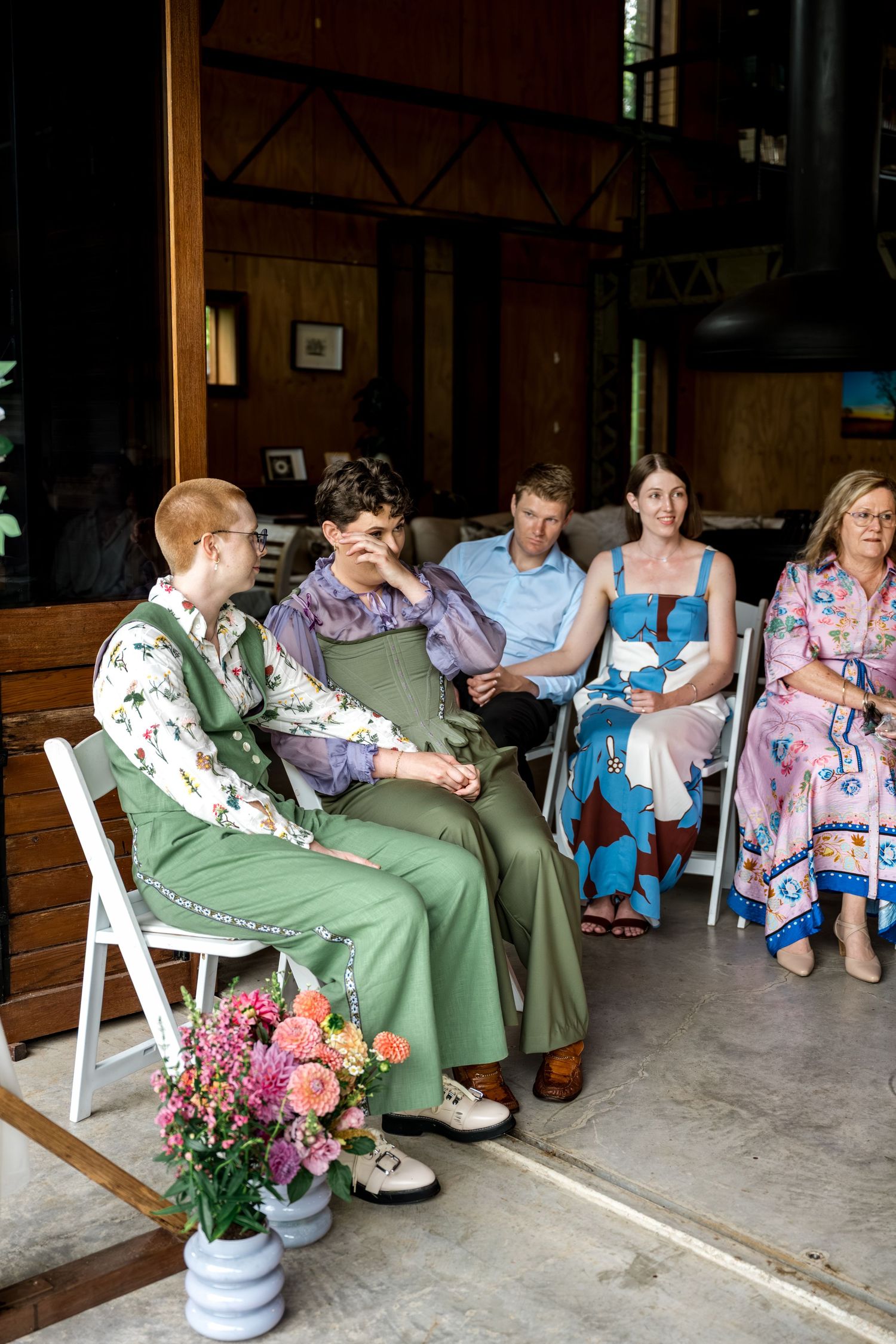 Wedding guests seated in white chairs during an intimate ceremony at a timber venue.
