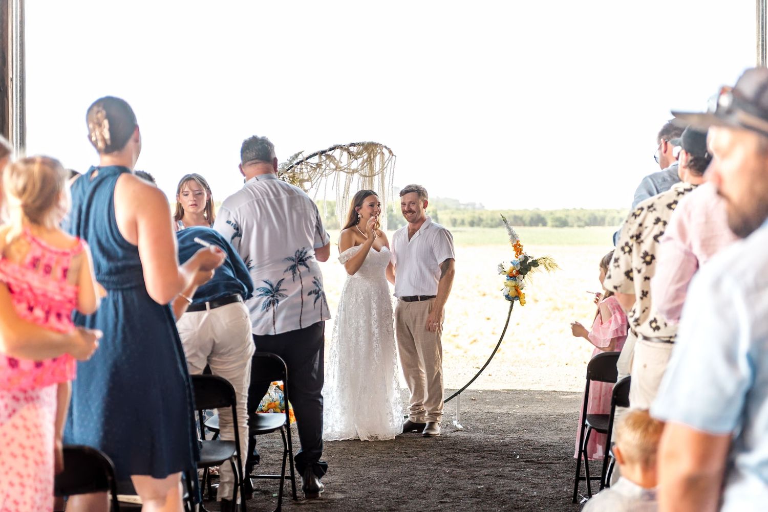 Bride and groom at altar in rustic barn surrounded by wedding guests.