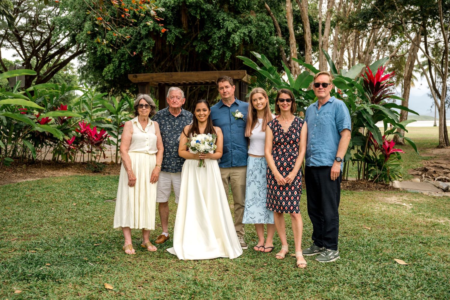 Wedding party family portrait with bride and groom posing in lush tropical garden setting at Little Cove, Port Douglas.