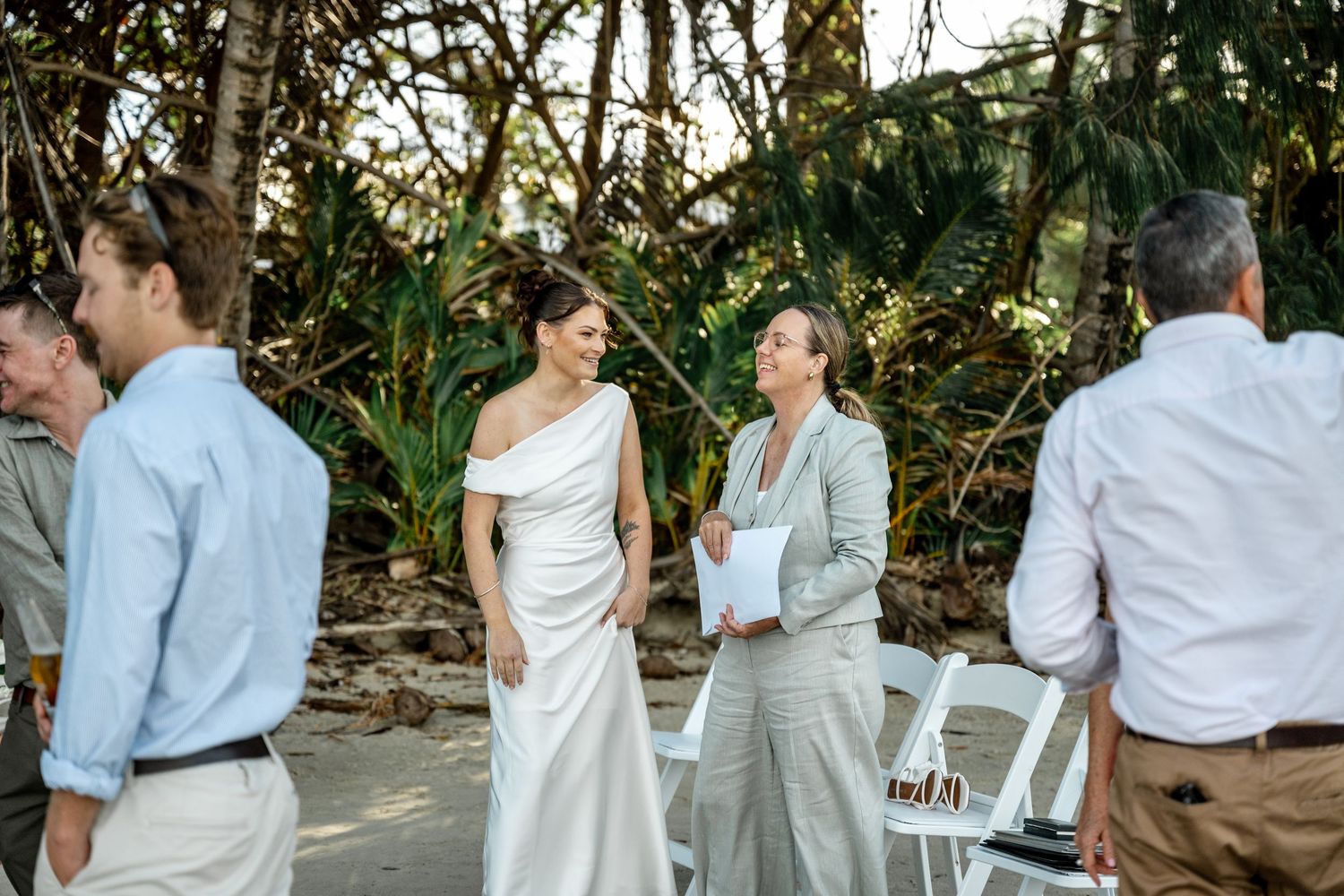 Bride in white gown smiling with female officiant at tropical beach wedding at Four Mile Beach, Port Douglas.