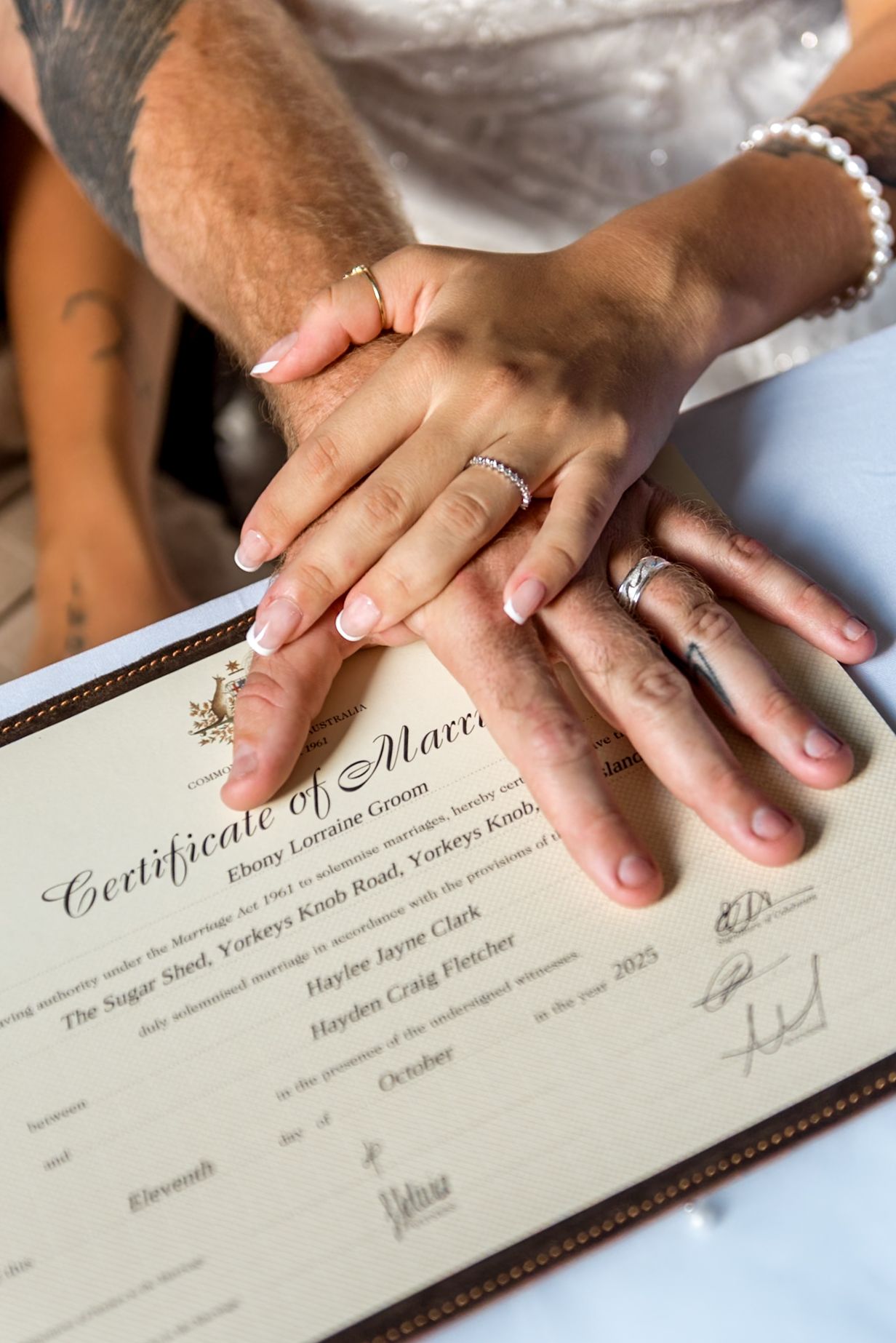 Newlyweds display wedding rings over signed Certificate of Marriage document.