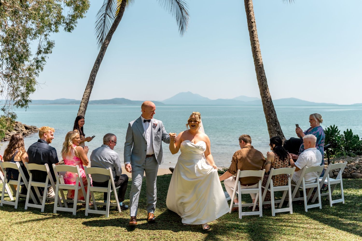 Newlywed couple recessional along tropical beach wedding aisle.