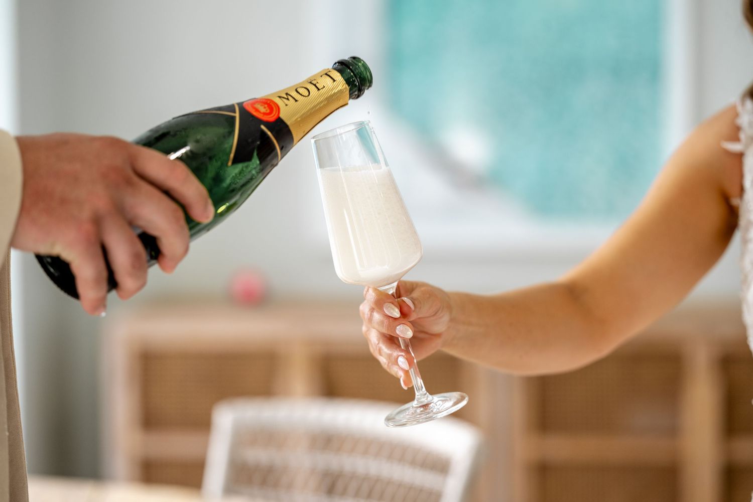 Moet Chandon champagne being poured into a flute glass held by a woman at a wedding reception.