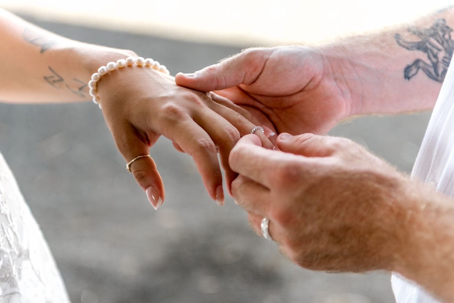 Close-up of groom placing wedding ring on bride's finger during ceremony.