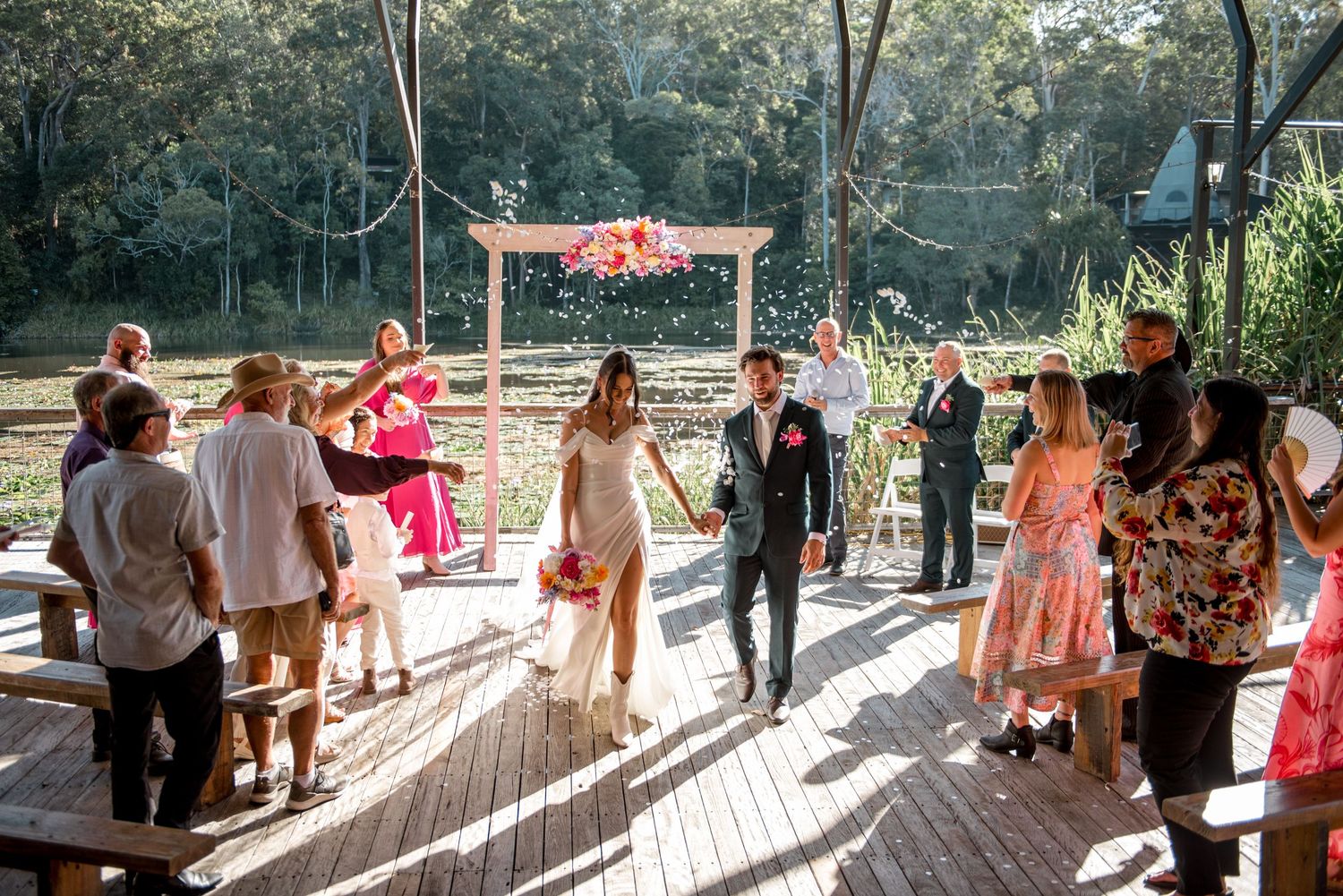 Newlyweds walking down aisle as guests celebrate with confetti.
