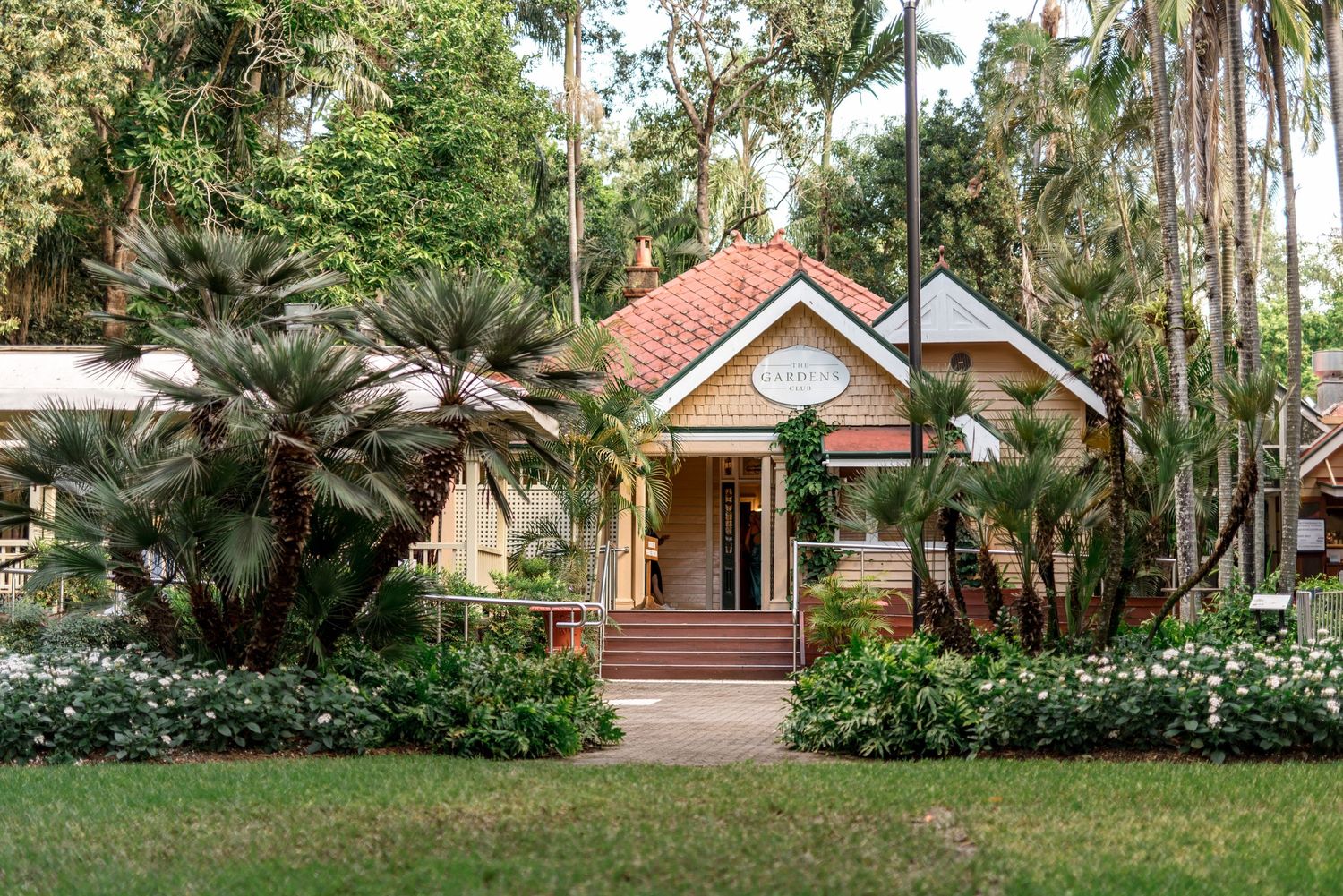 Charming heritage cottage venue surrounded by lush tropical gardens, palm trees, and manicured lawns.