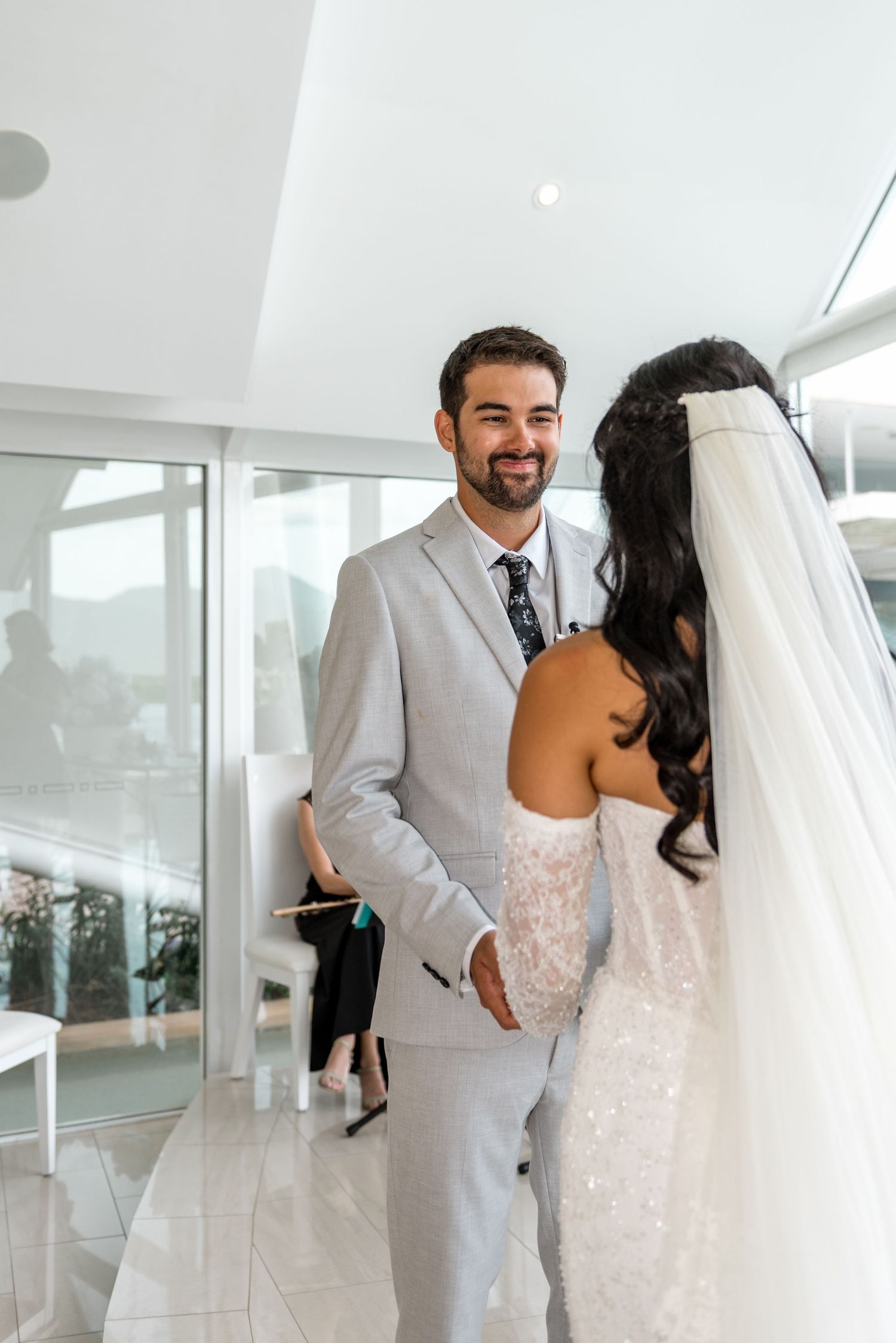 Groom smiles warmly at bride during intimate wedding ceremony exchange in glass venue.