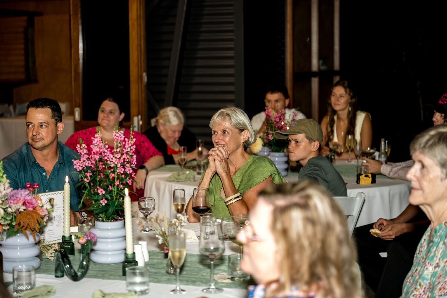 Guests seated at elegantly decorated tables during an outdoor evening dinner party event.