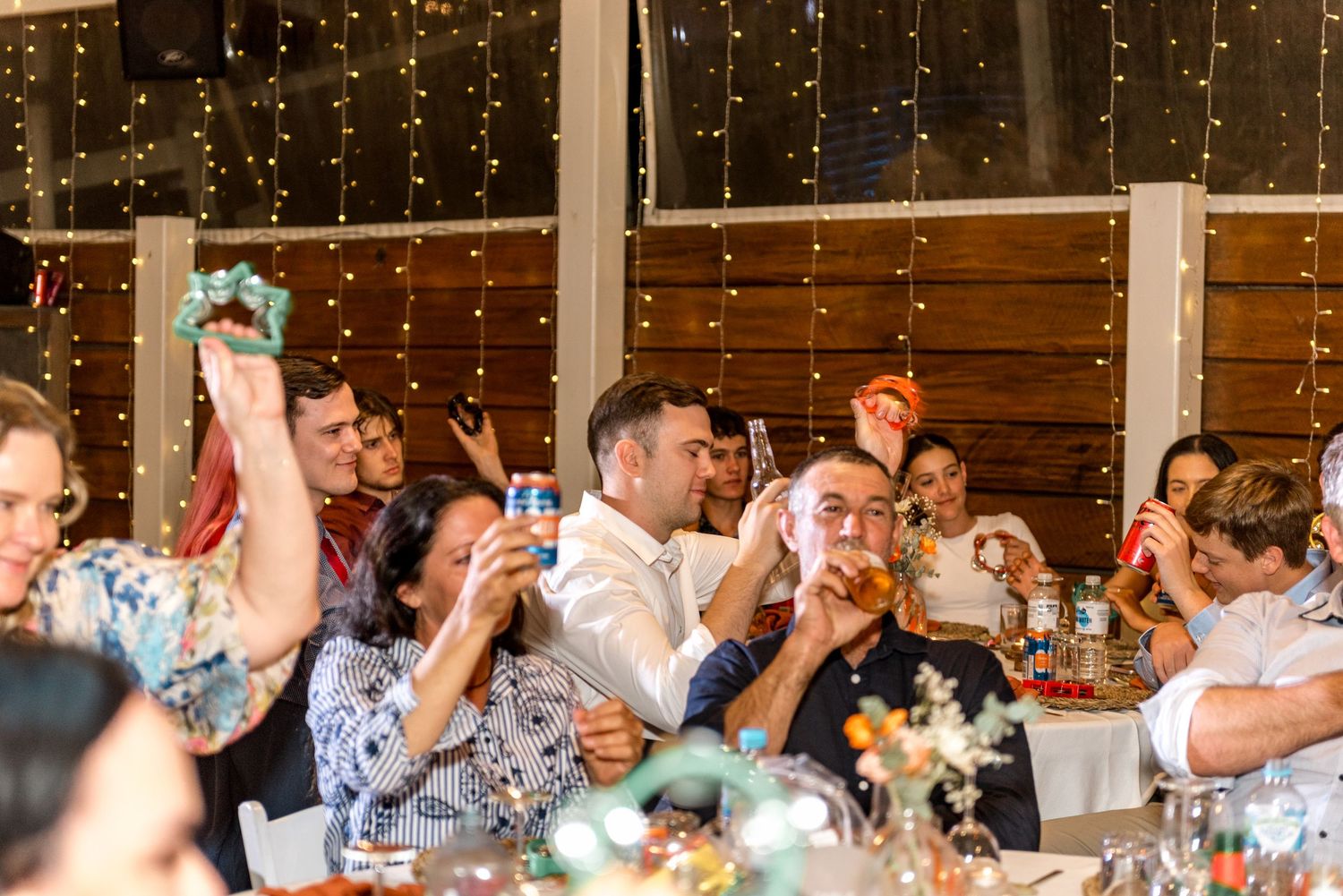 Wedding guests raising drinks in a toast during reception celebration.