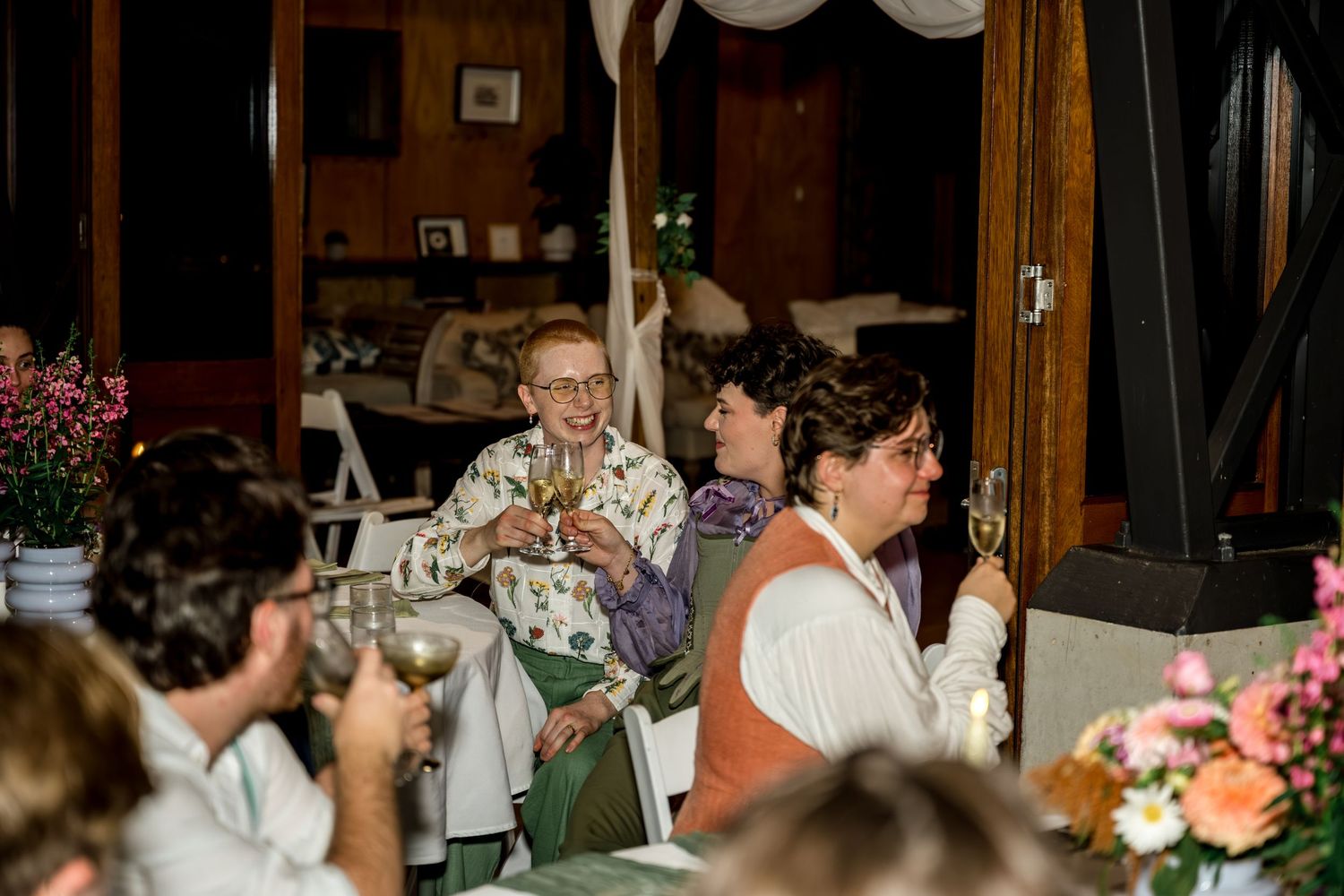 Wedding guests raising glasses in a toast during a reception celebration.