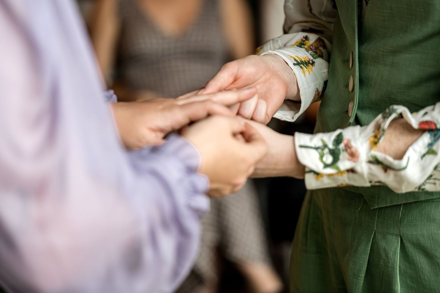 Close-up of two people exchanging wedding rings during an intimate ceremony outdoors.