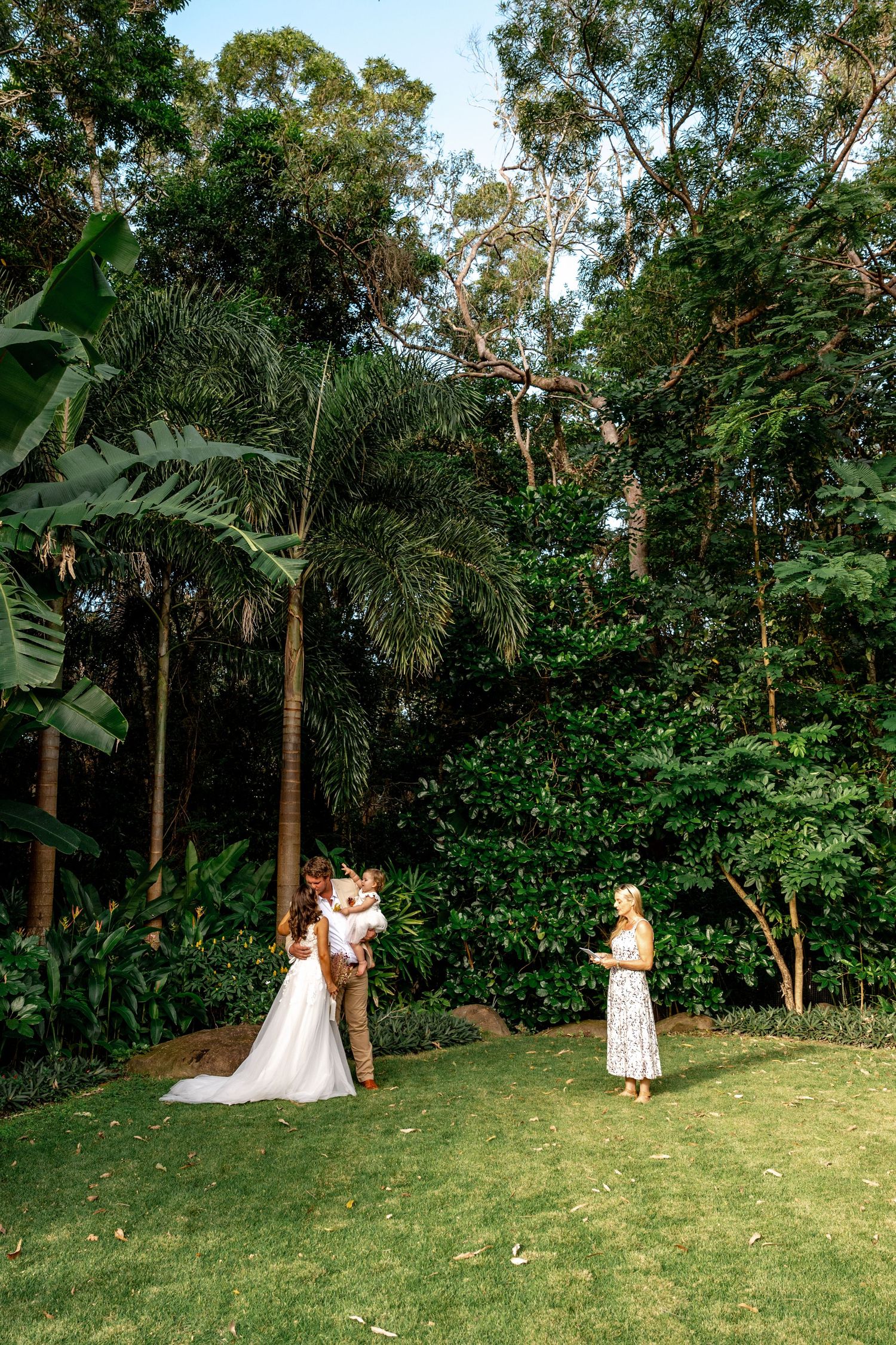 A couple shares their first kiss during an intimate outdoor wedding ceremony in a lush garden.