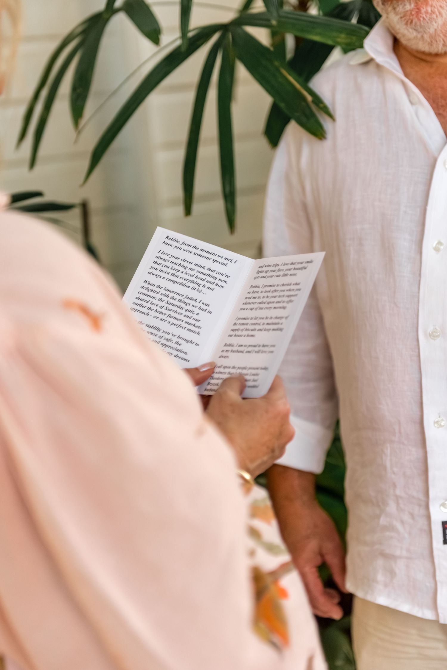 Close-up of bride reading handwritten wedding vows from a folded paper card.