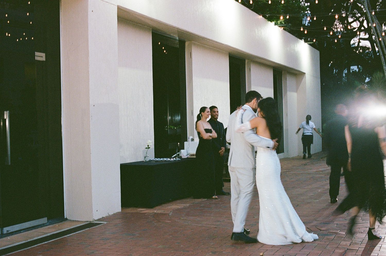 Bride and groom share first dance outside white modern wedding venue.