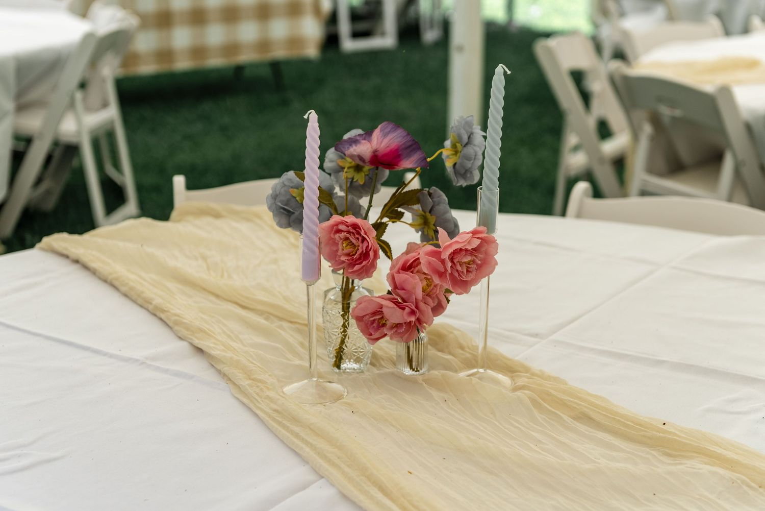 Pink roses and candles arranged on a burlap table runner as a wedding reception centerpiece decoration.