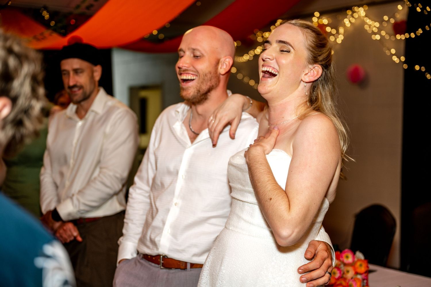 Laughing bride and groom share a joyful moment together at their wedding reception.