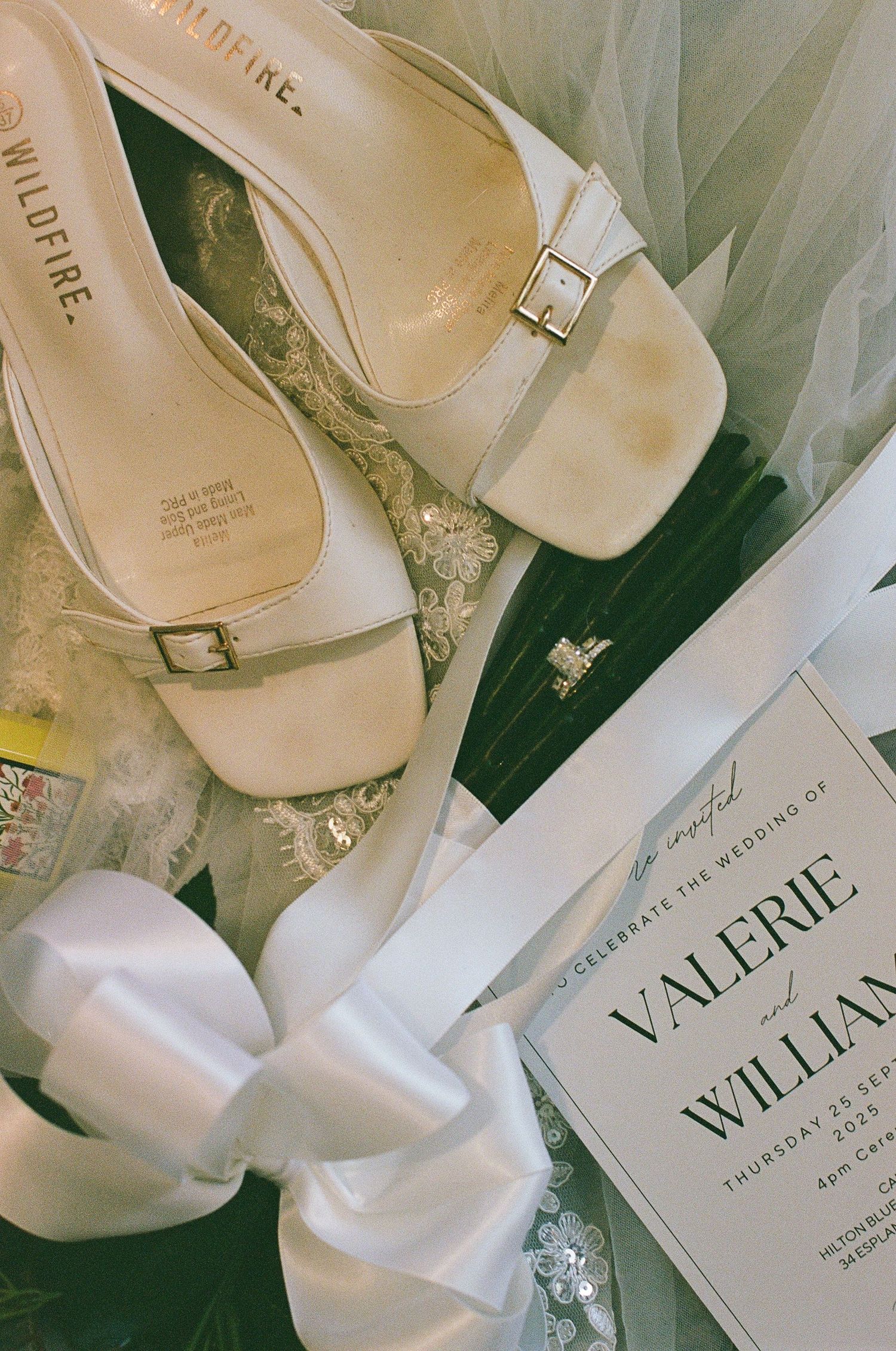White bridal heels and wedding invitation for Valerie and William displayed elegantly with a satin bow.