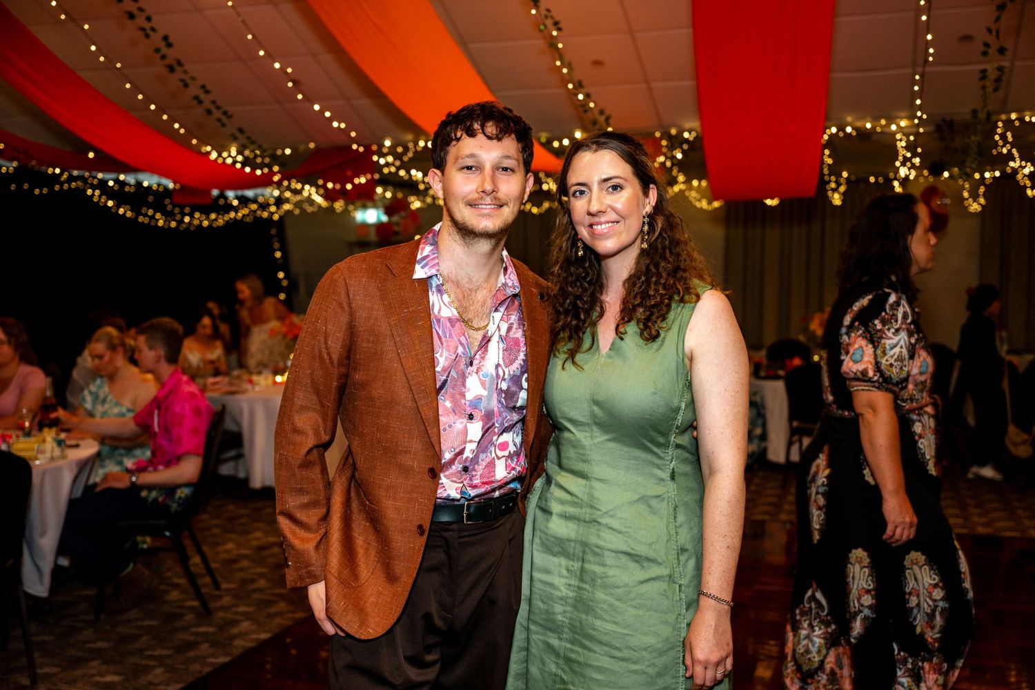 Smiling couple poses together at a warmly lit wedding reception venue.