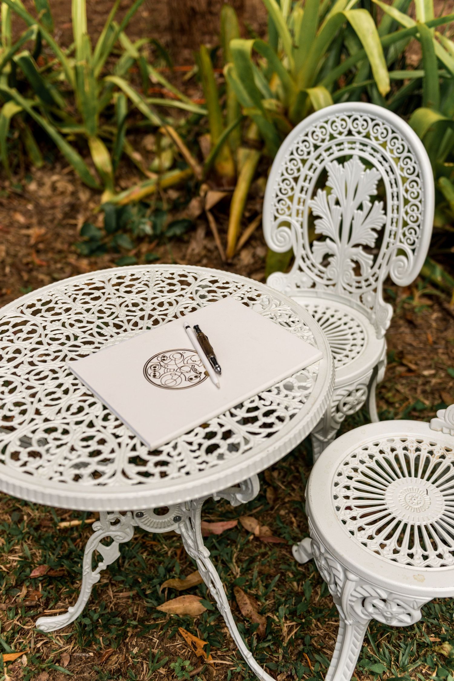 Elegant white cast iron garden table and chairs with guest book and pen.