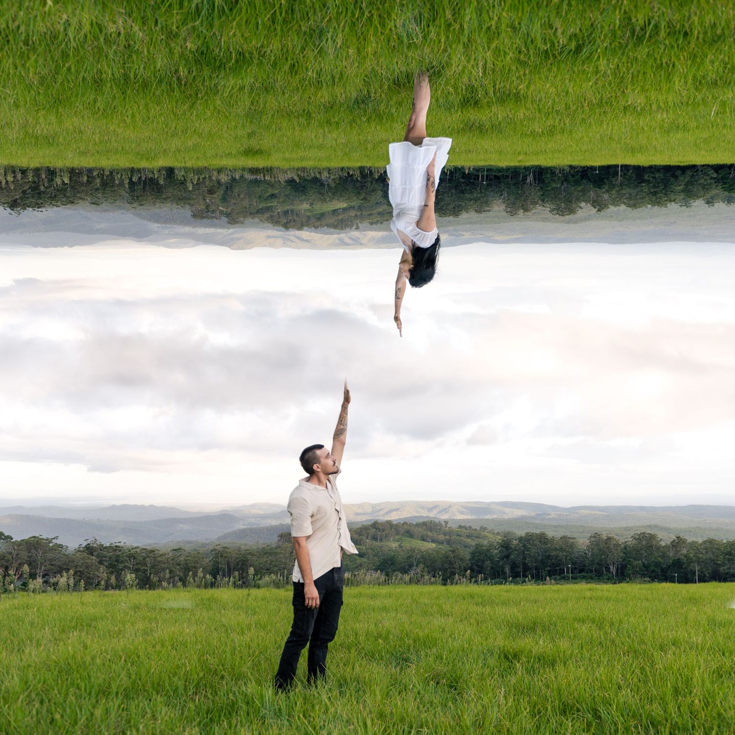 Creative mirrored photo of man reaching up to woman in a lush green field.