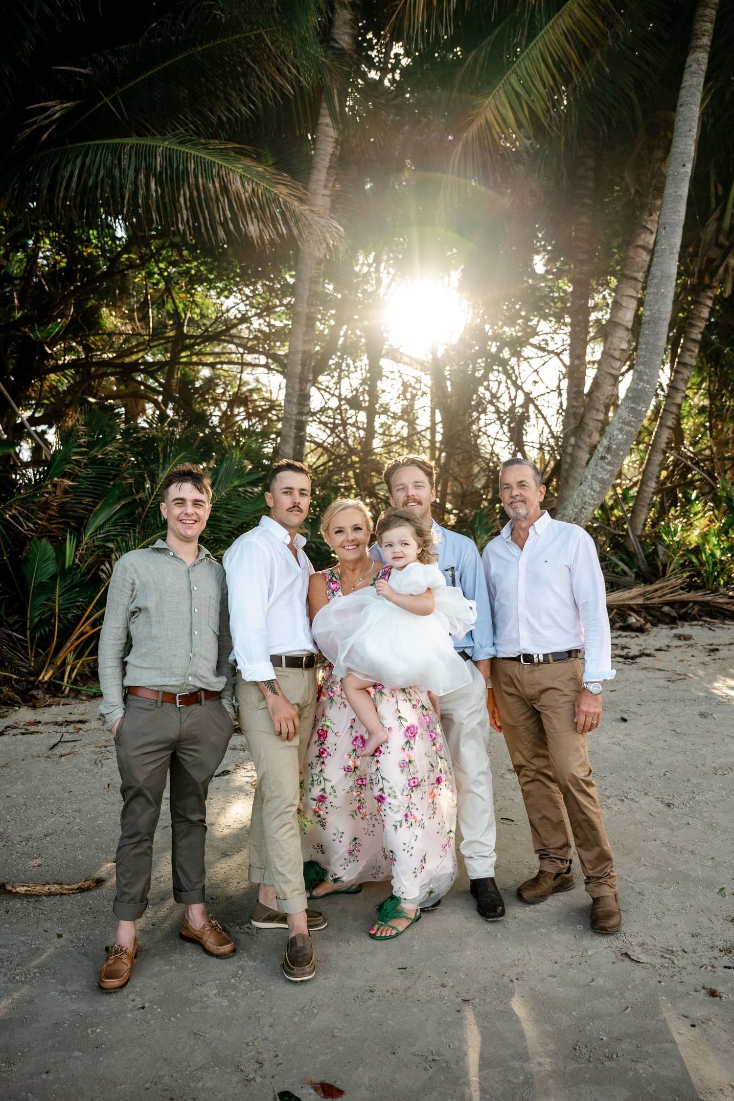 Family group portrait of six adults and a child on a tropical beach at sunset at Four Mile Beach, Port Douglas.
