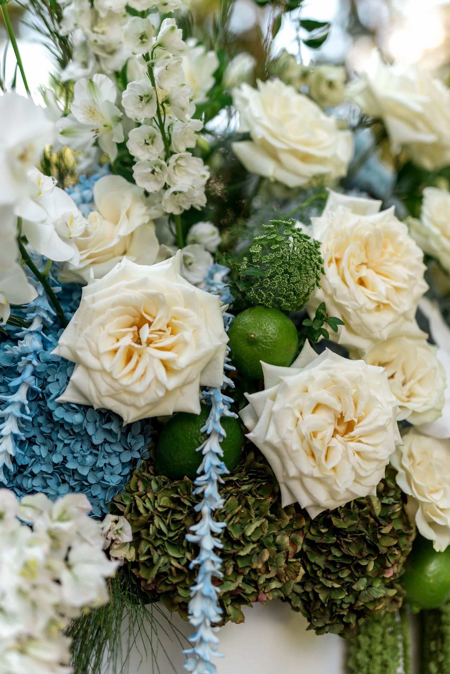 Close-up of a luxurious wedding floral arrangement with white roses, blue hydrangeas, and green accents.