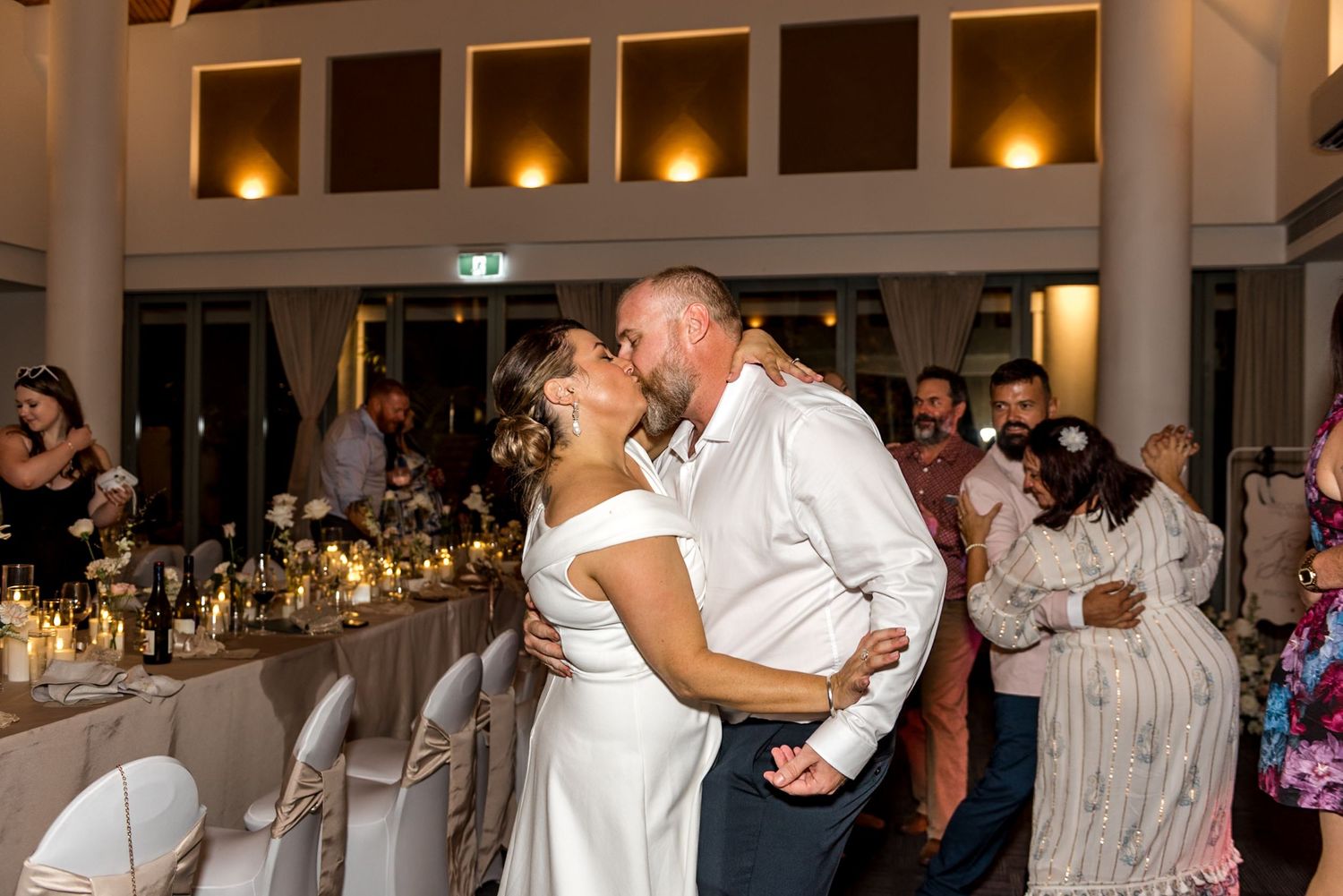 Bride and groom share a passionate kiss on the wedding reception dance floor.