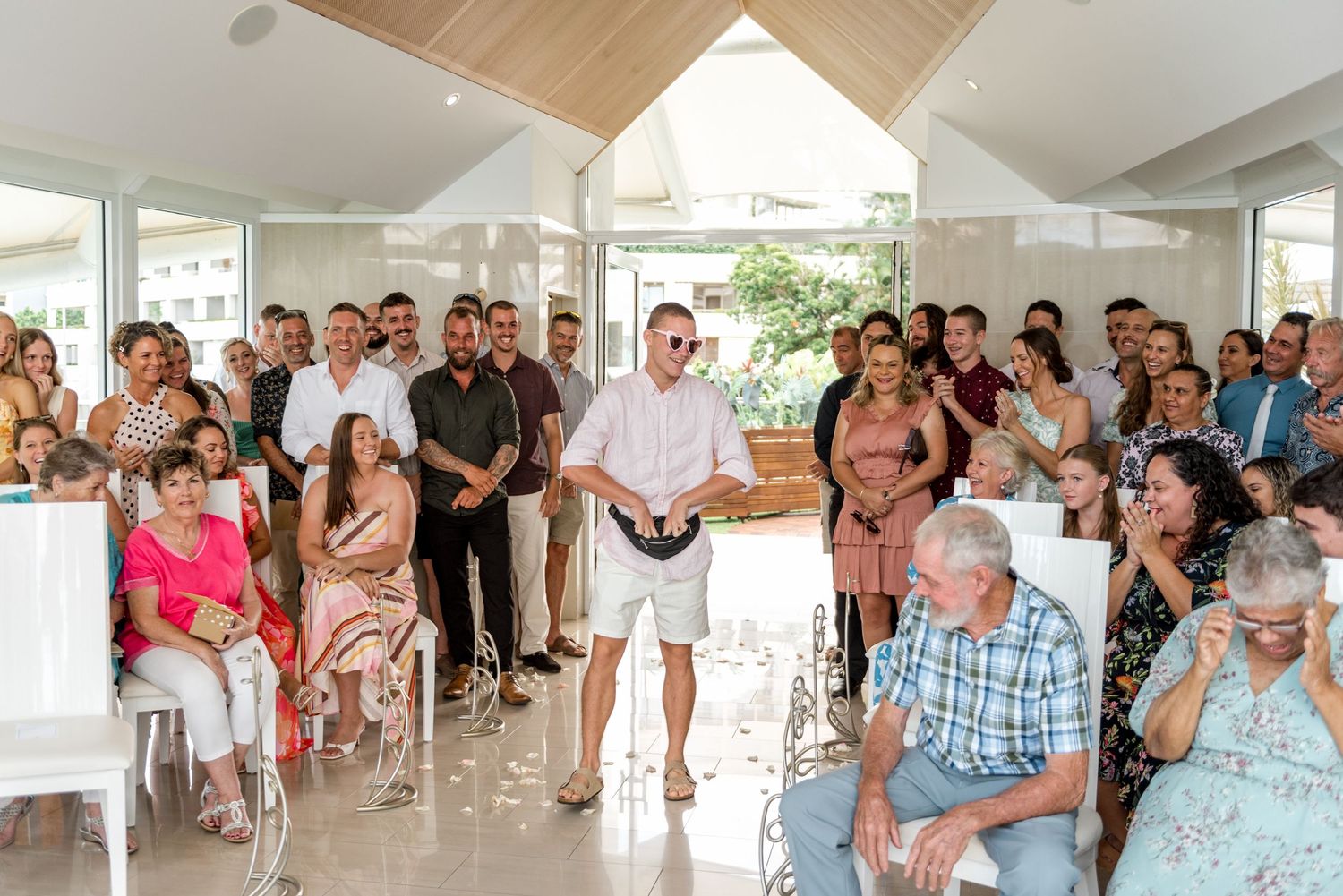 Guests standing and seated inside a sunlit wedding chapel during the ceremony.