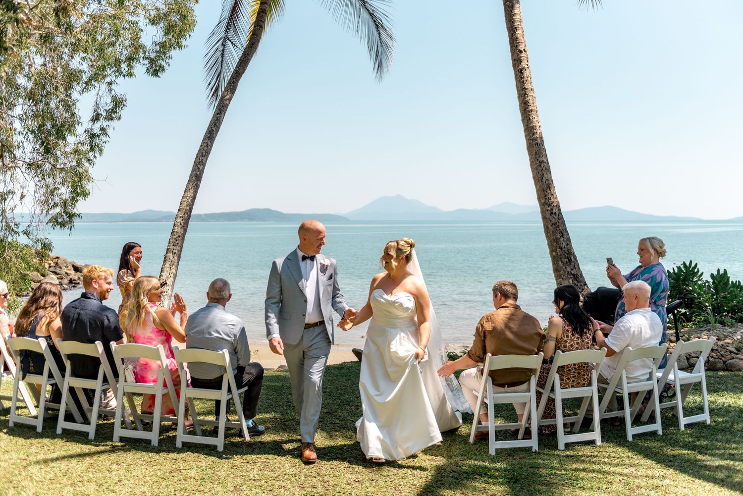 Bride and groom walking hand in hand after tropical beach wedding.