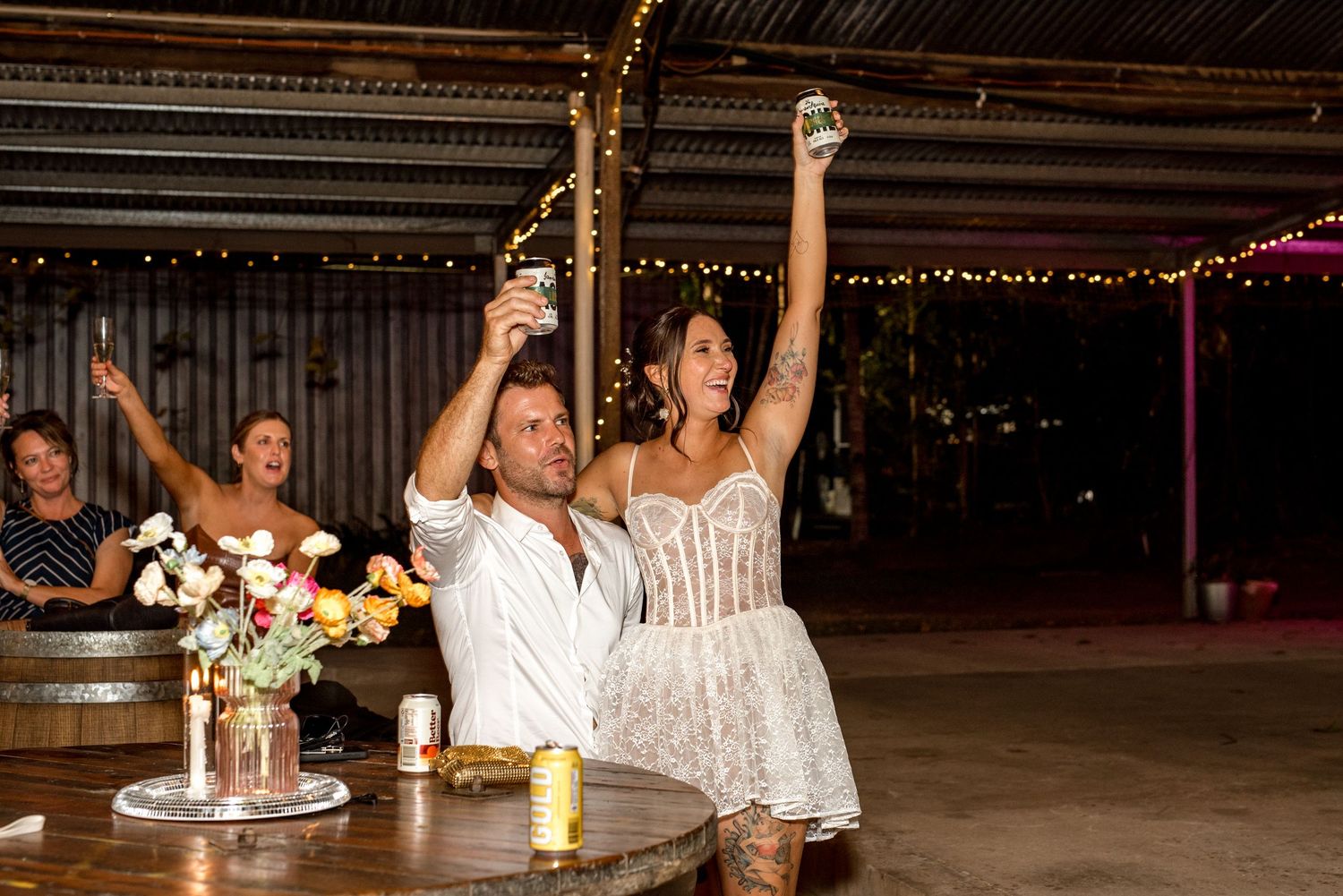 Bride and groom raising glasses in a celebratory toast at their rustic barn wedding reception.