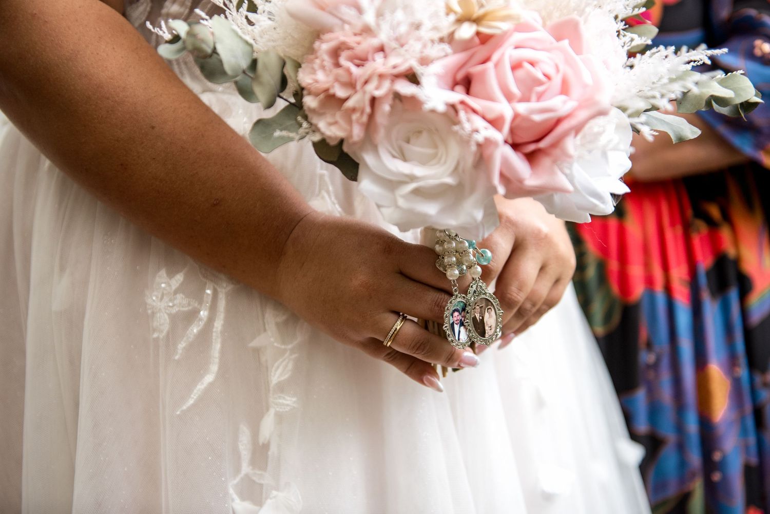 Bride holding a pink and white wedding bouquet with pearl and crystal jewelry on her hands.