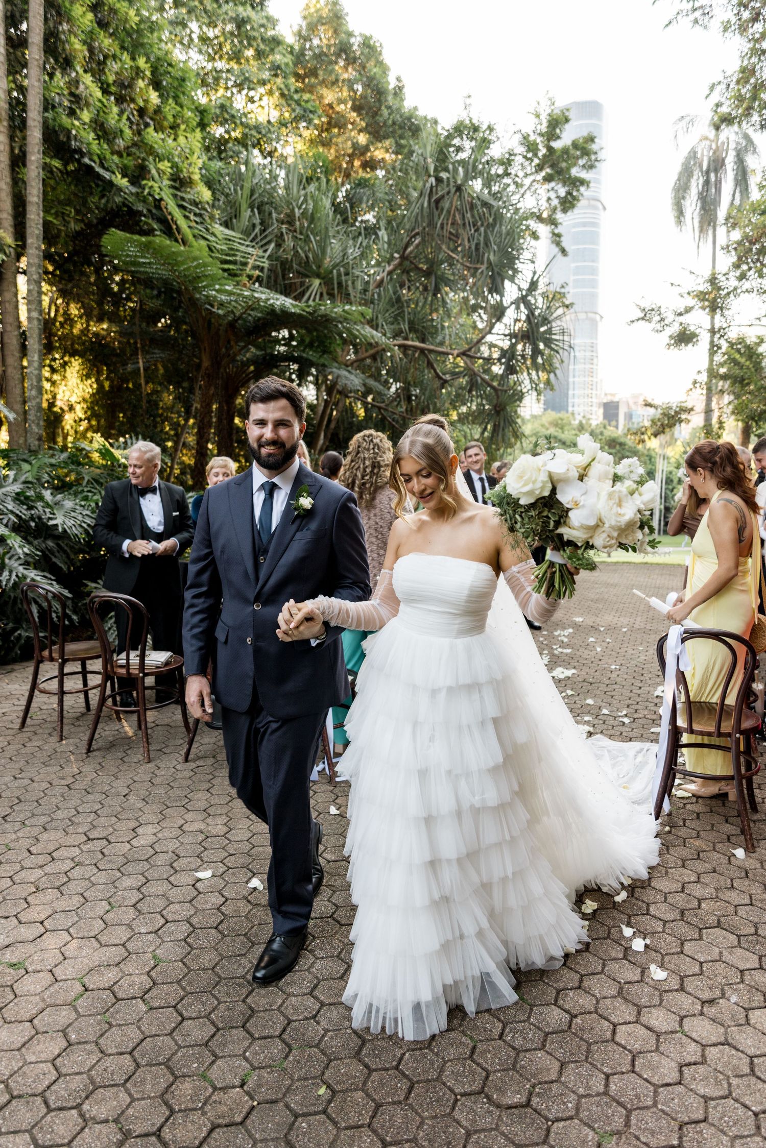 Bride and groom walk hand-in-hand down the aisle after their outdoor garden wedding ceremony.