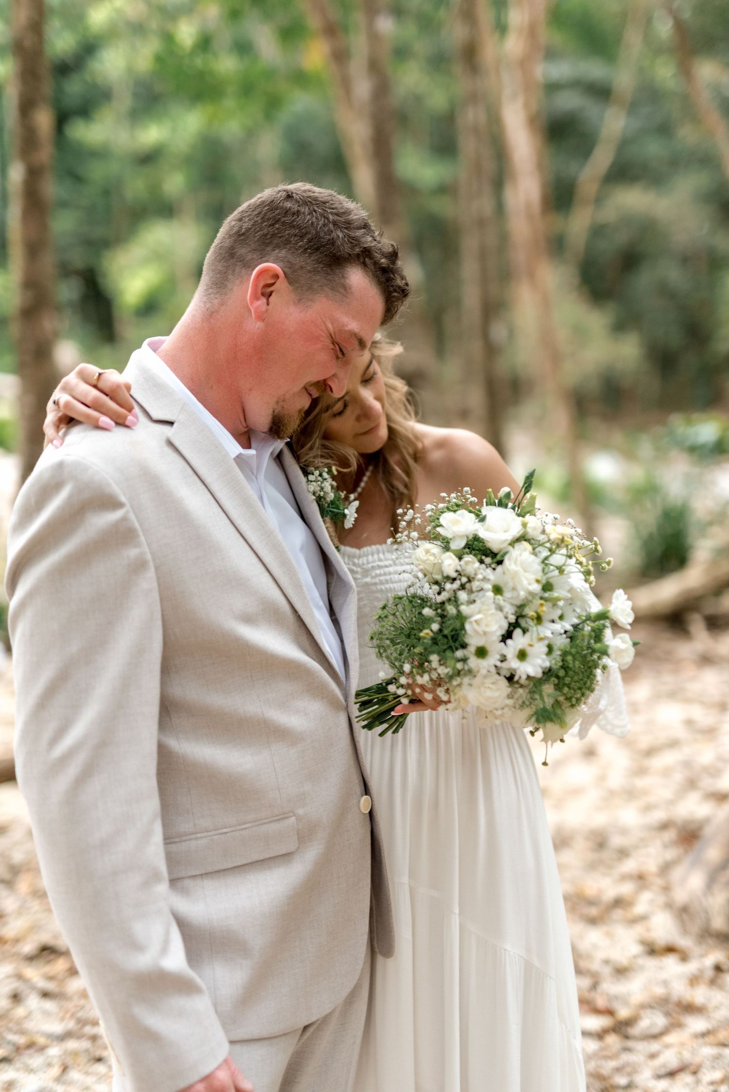 Bride and groom share an intimate moment together in a natural forest wedding setting.