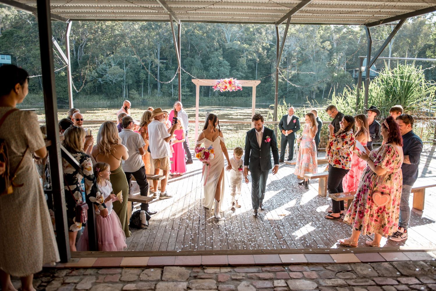 Newlyweds walking down aisle surrounded by cheering wedding guests.