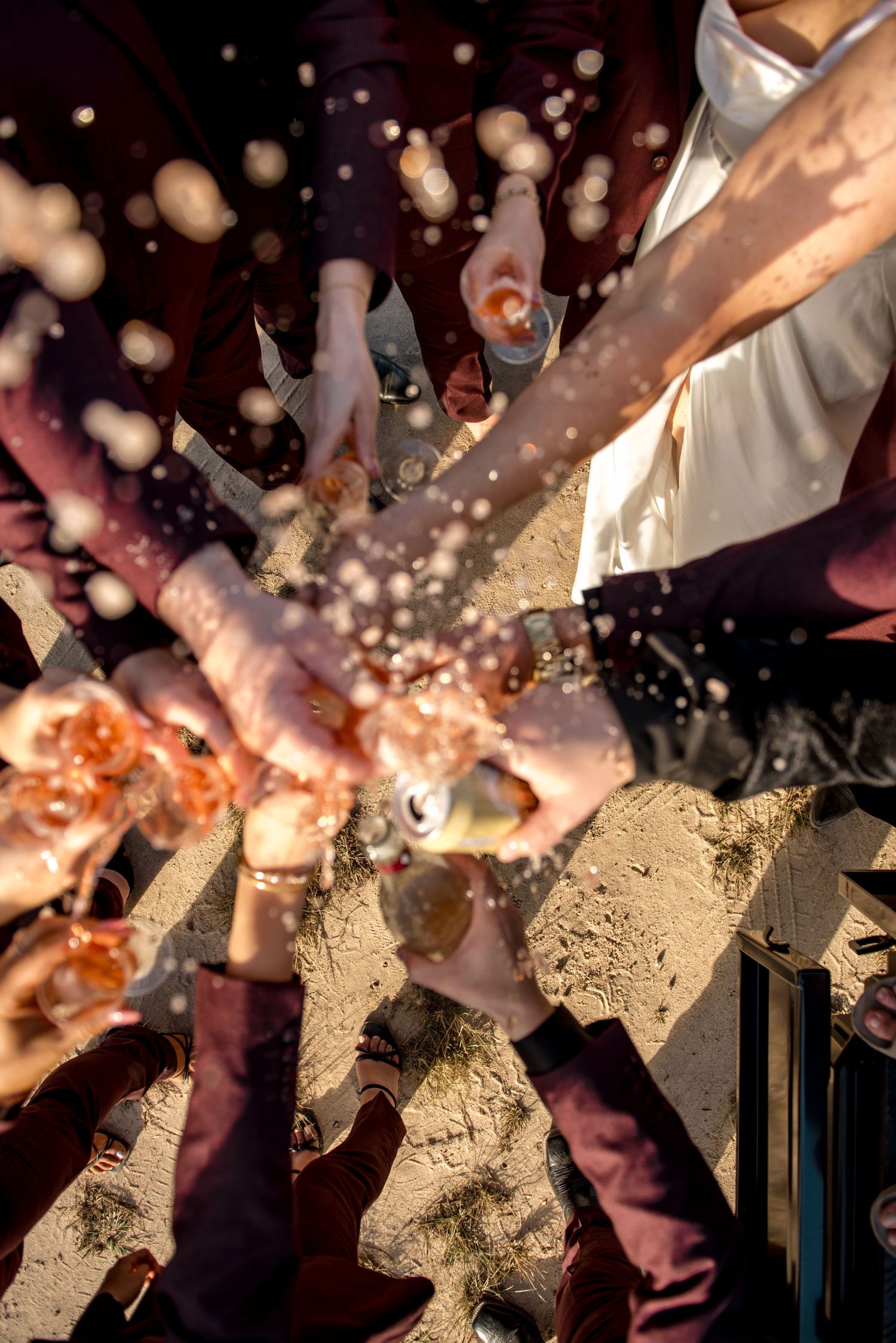 Wedding party champagne toast splash captured from above in golden sunlight.