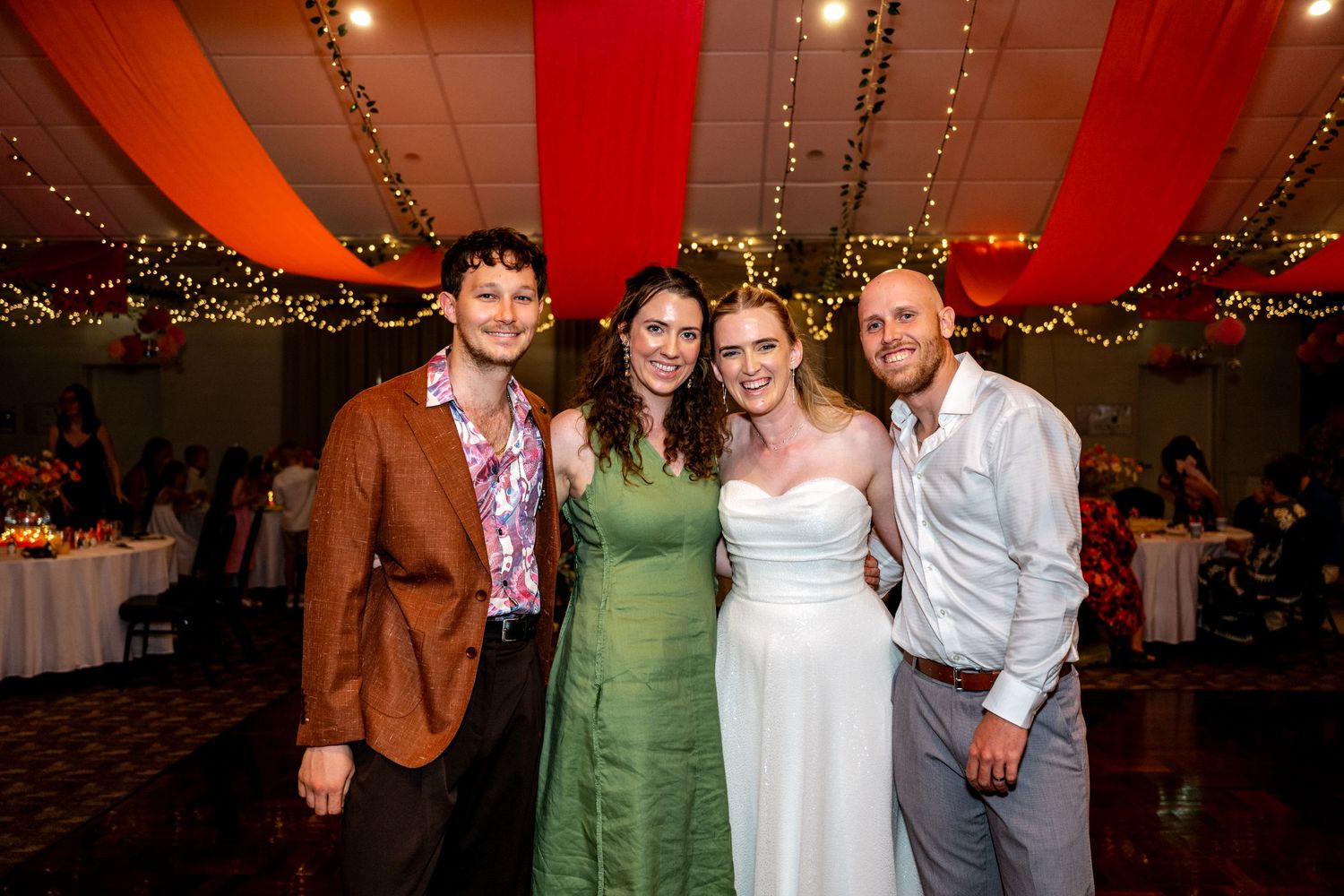 Bride and groom pose with two friends at their wedding reception.