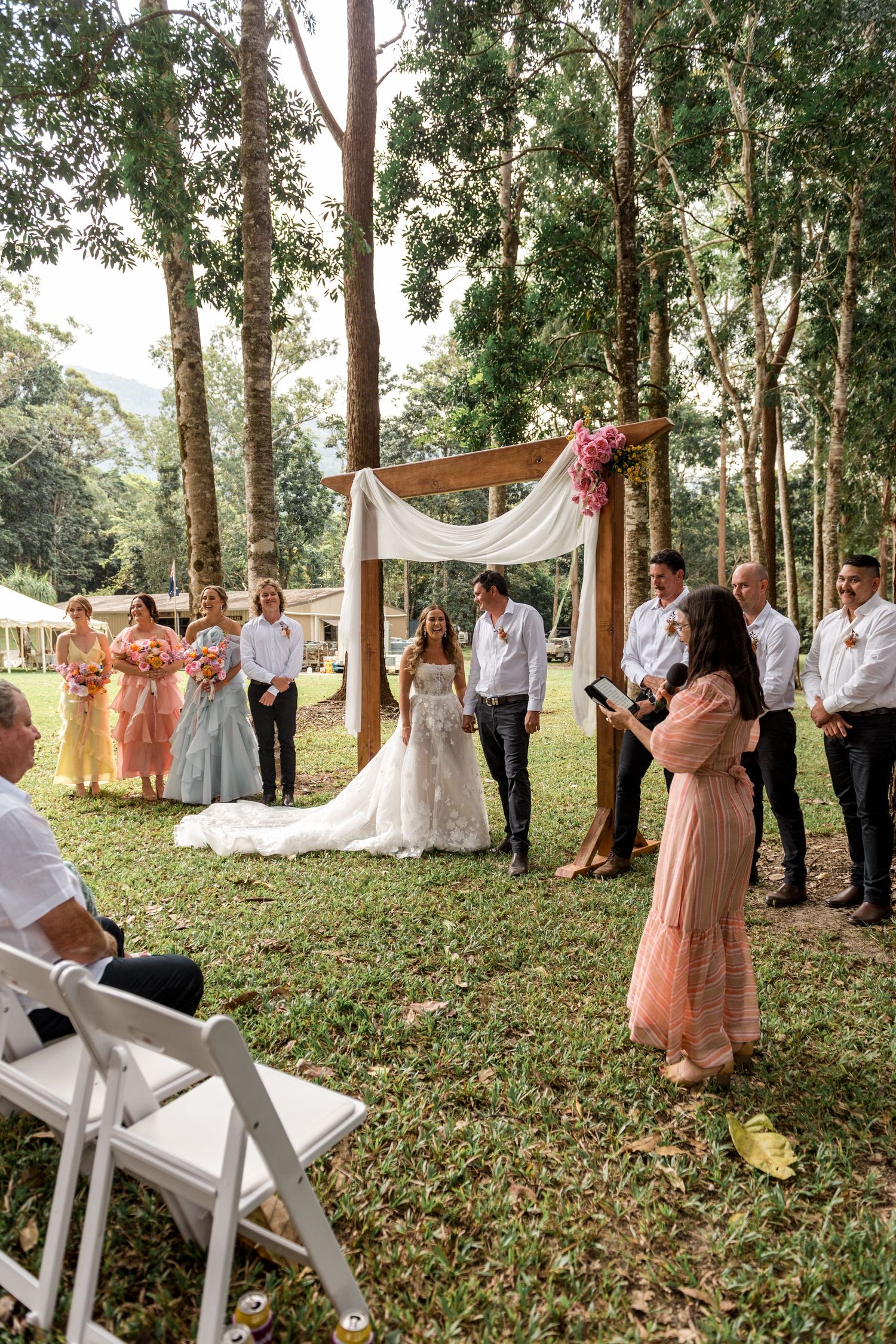 Officiant reading at an outdoor forest wedding ceremony with bride and groom at the altar.