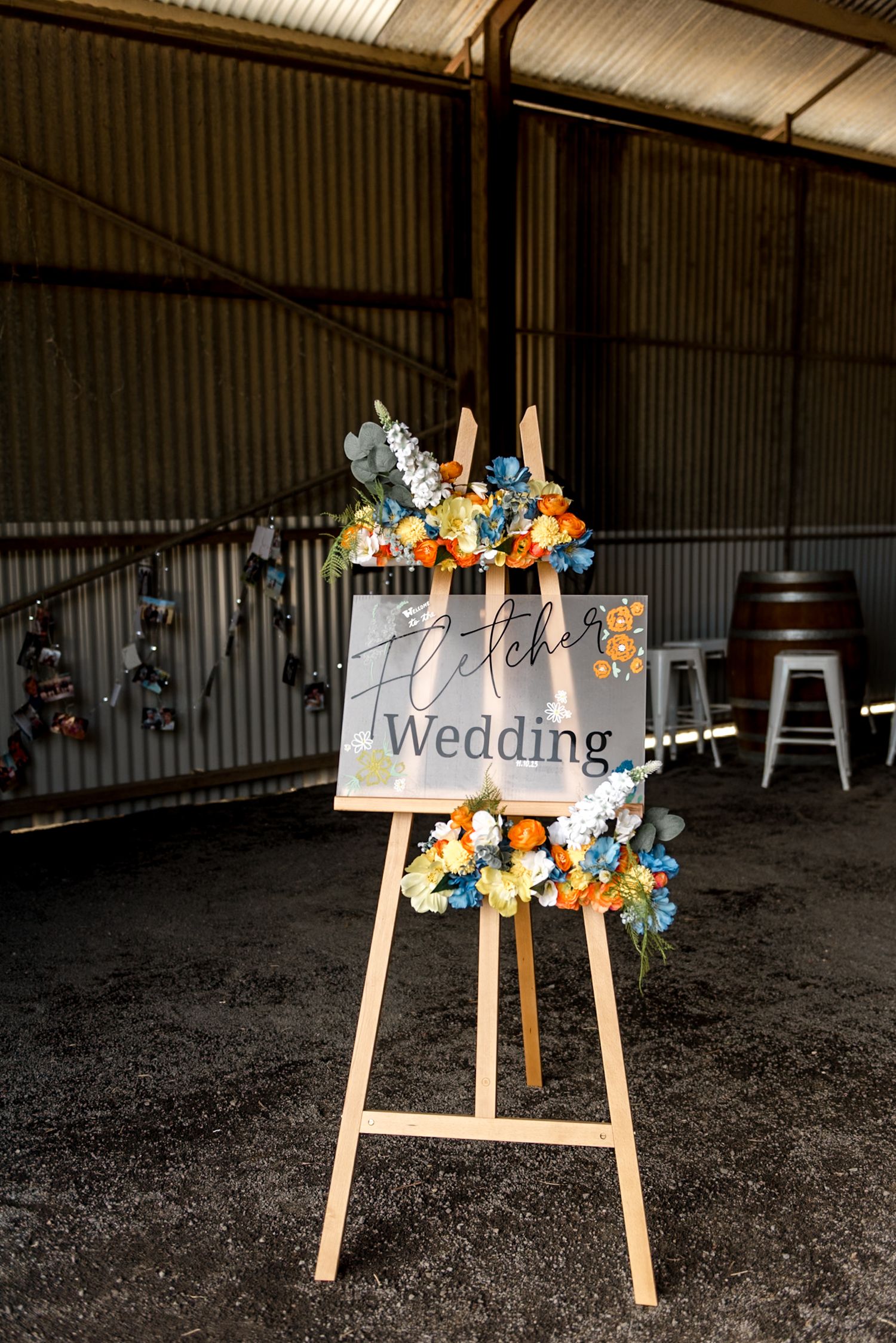 Elegant Fletcher Wedding sign on wooden easel adorned with vibrant blue and orange floral arrangements.