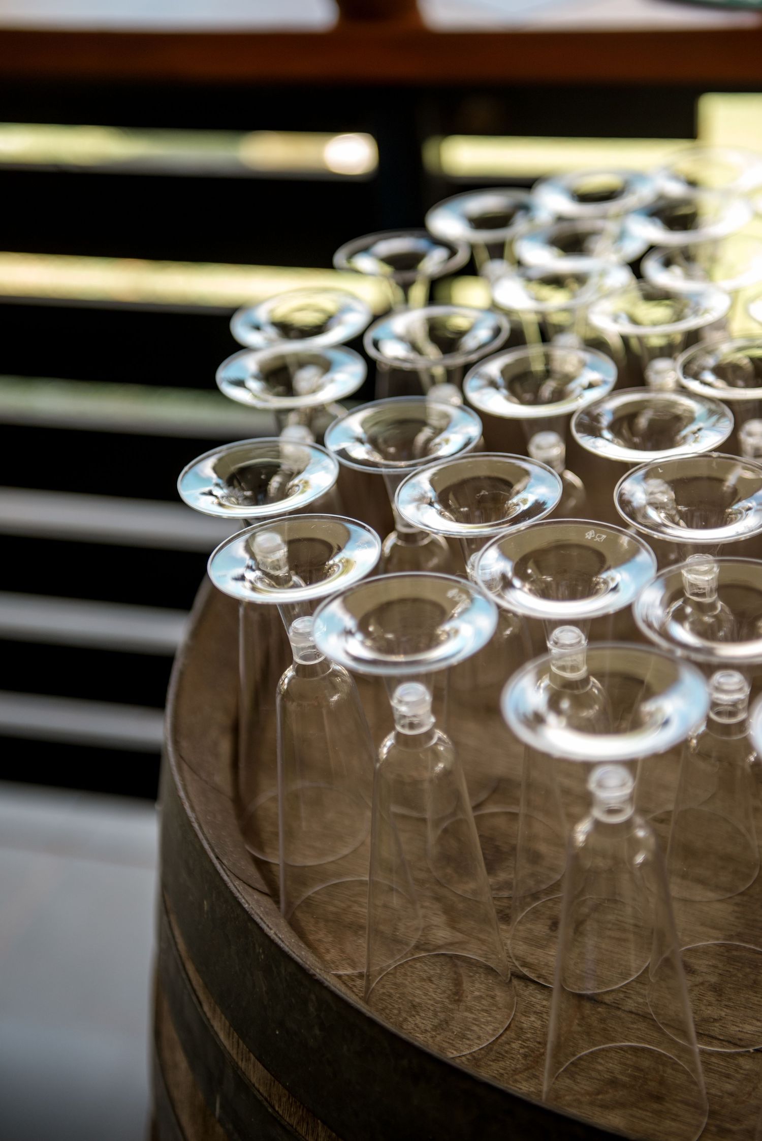 Multiple champagne flutes turned upside down displayed on a rustic wooden barrel for a wedding reception.