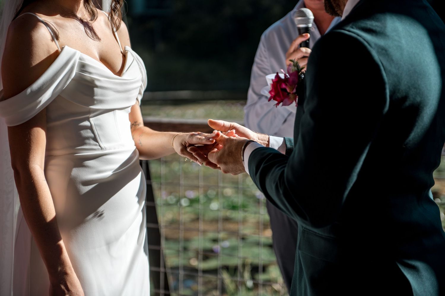 Bride and groom exchanging rings during outdoor wedding ceremony.