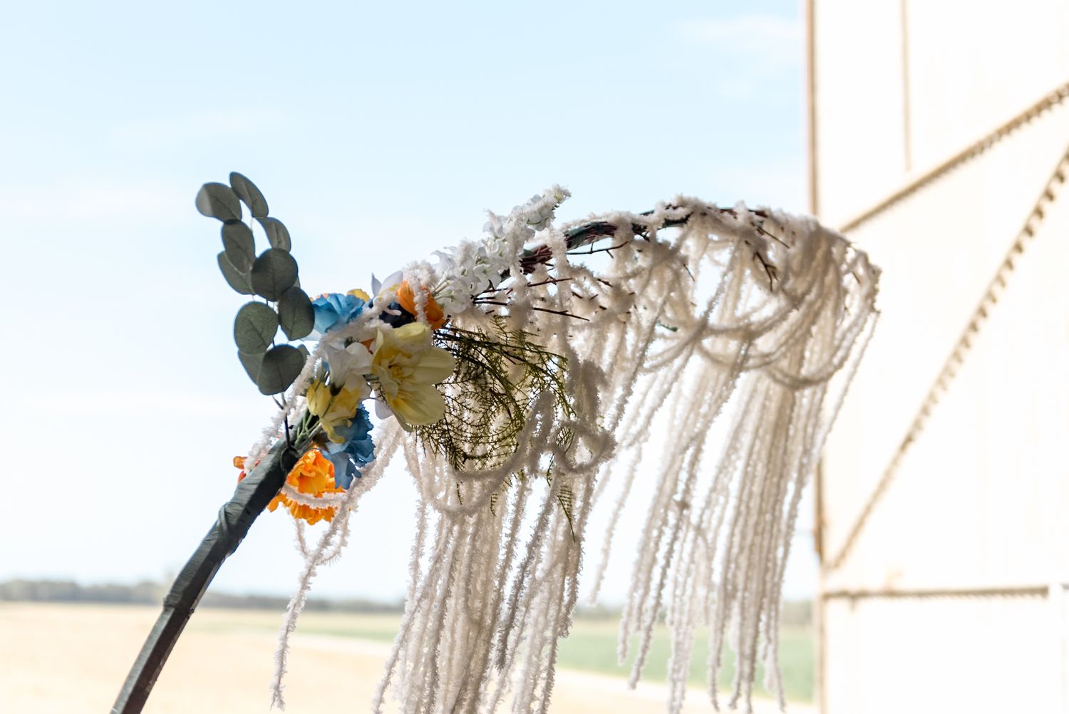Close-up of a decorative dragonfly accent with macrame fringe on a wedding arch.