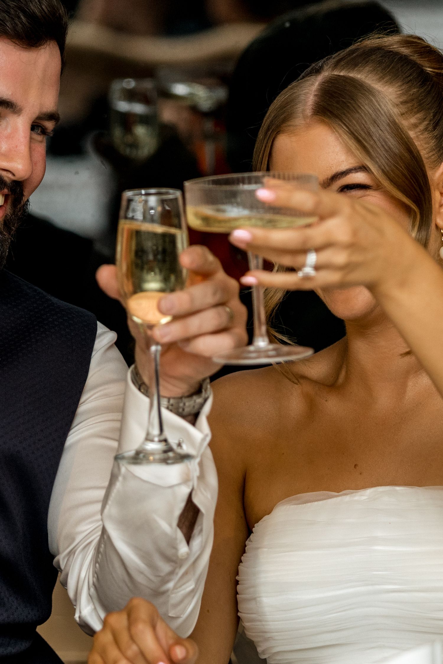 Bride and groom raising champagne glasses in a celebratory toast at their wedding reception.