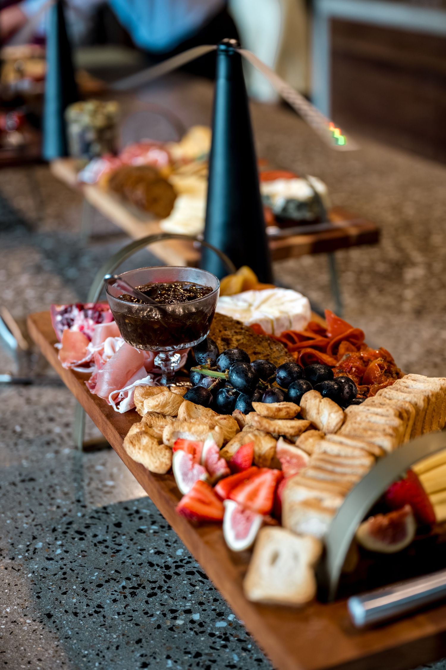 Gourmet charcuterie board featuring grapes, figs, cheese, cured meats, and jam at wedding.
