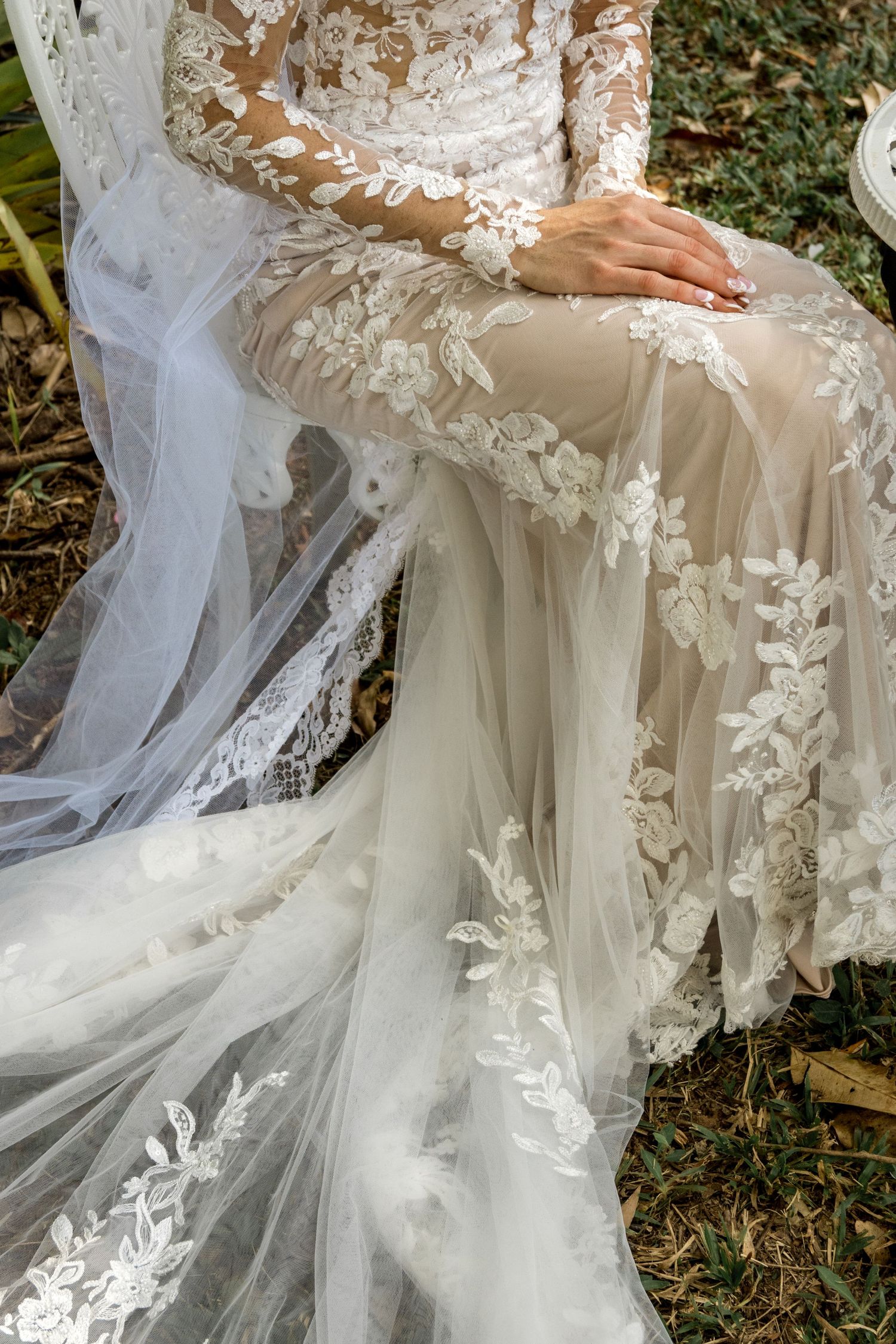 Close-up detail of bride's intricate floral lace wedding gown and veil.