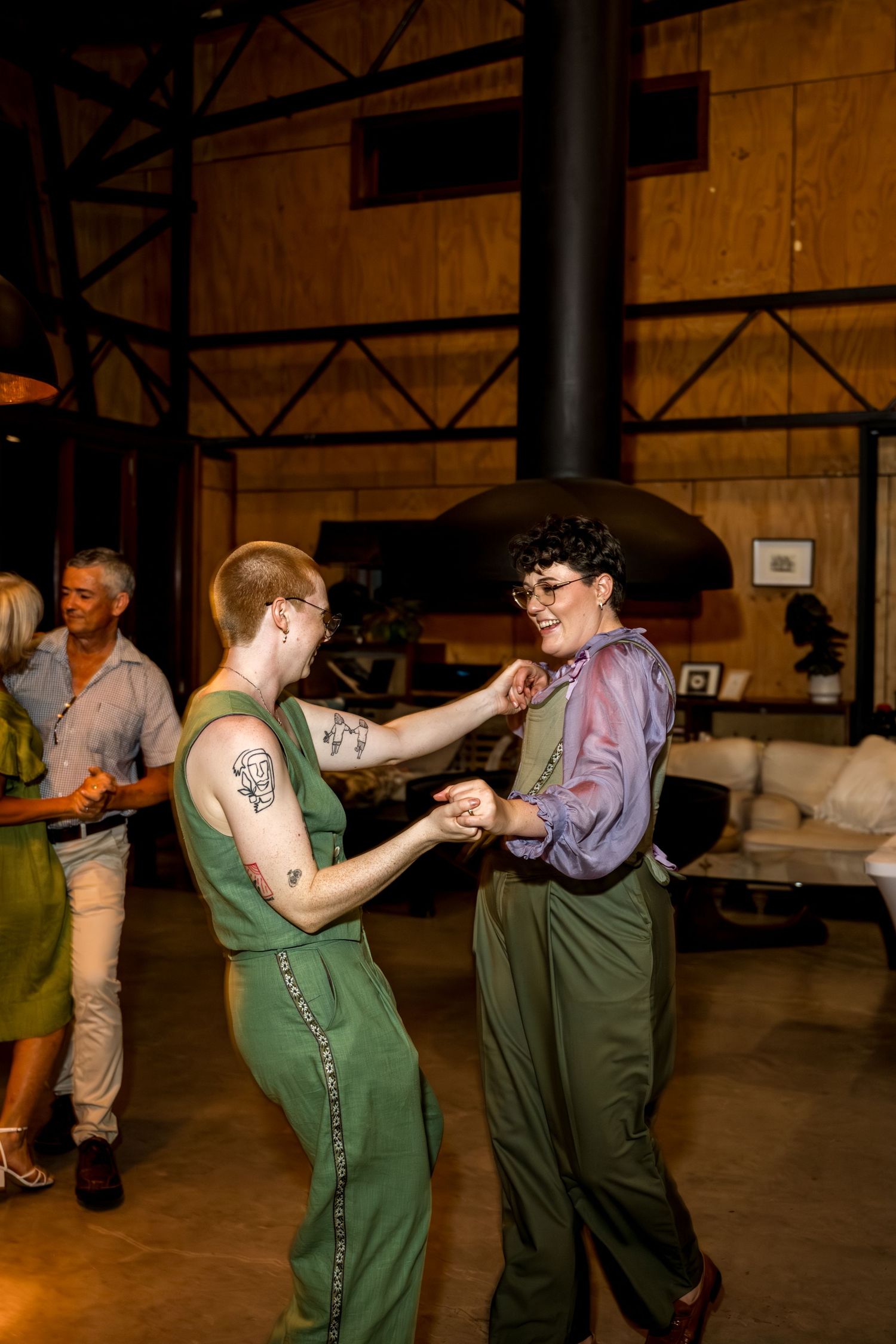Two people in matching green outfits share a first dance at their wedding reception.