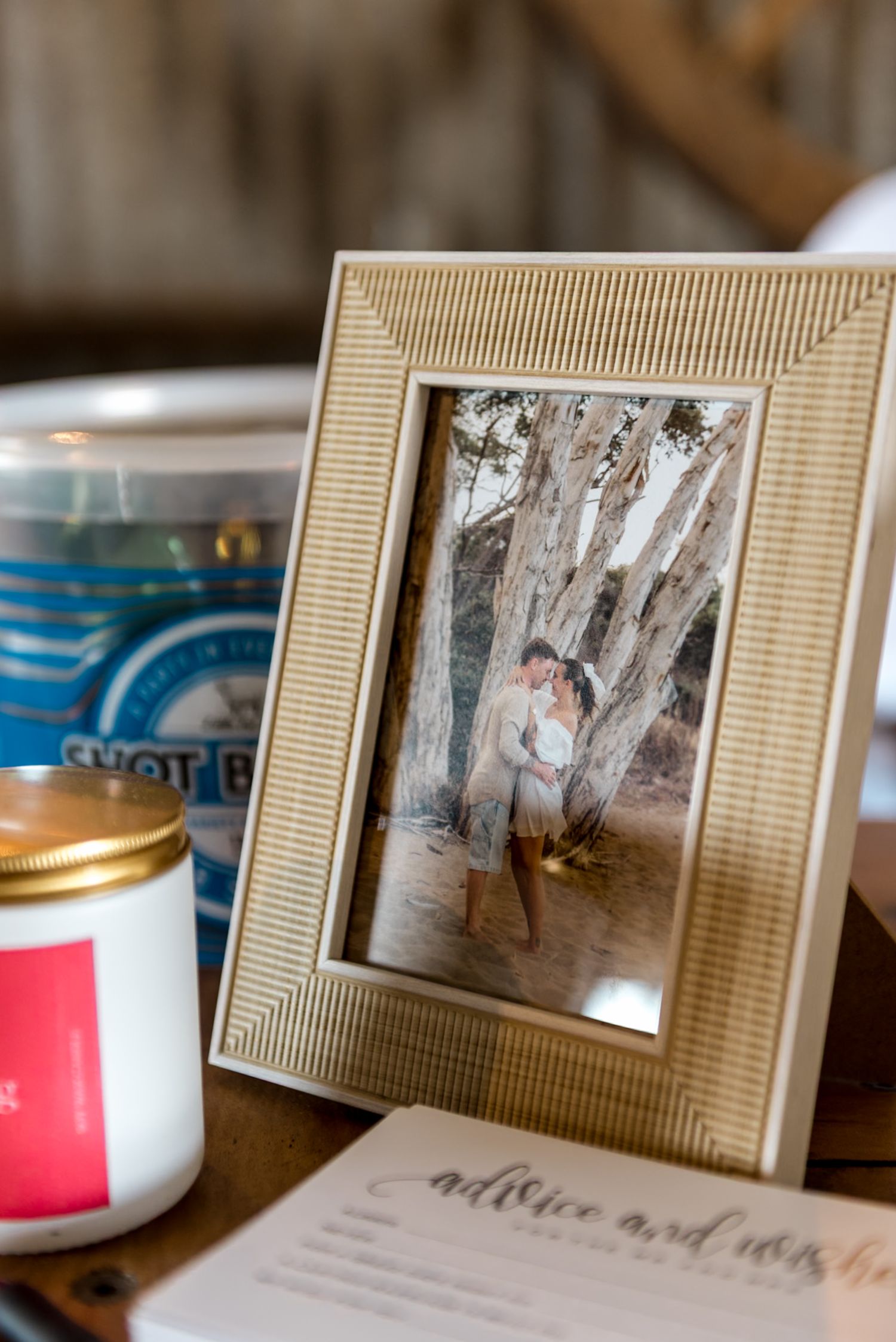 Gold framed engagement photo beside candles and advice cards on a wooden table.