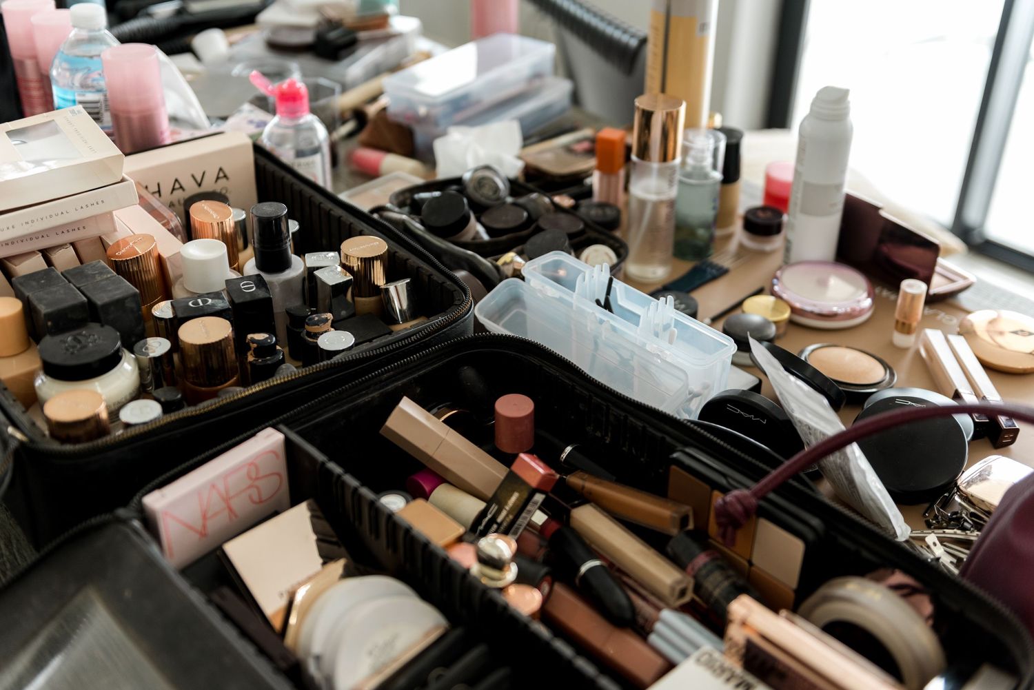 Professional makeup artist kit with an extensive collection of cosmetics, foundations, and beauty products spread on a surface.