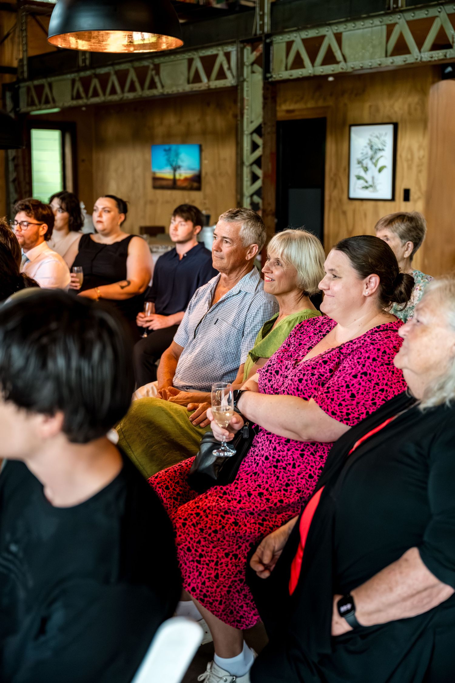 Guests seated and smiling during an intimate indoor wedding ceremony at a rustic timber venue.