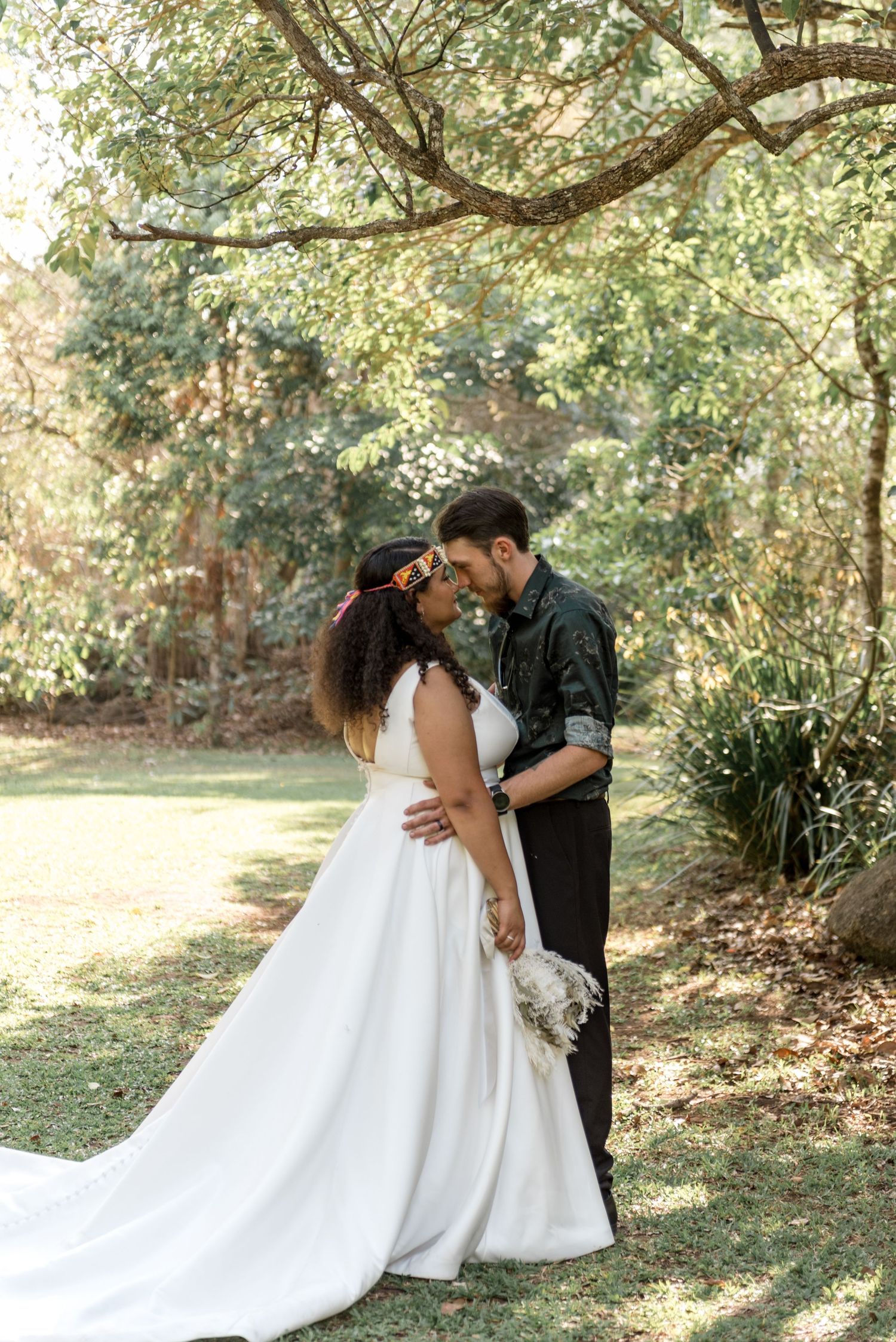 Bride and groom sharing a romantic kiss in a lush green garden setting on their wedding day.
