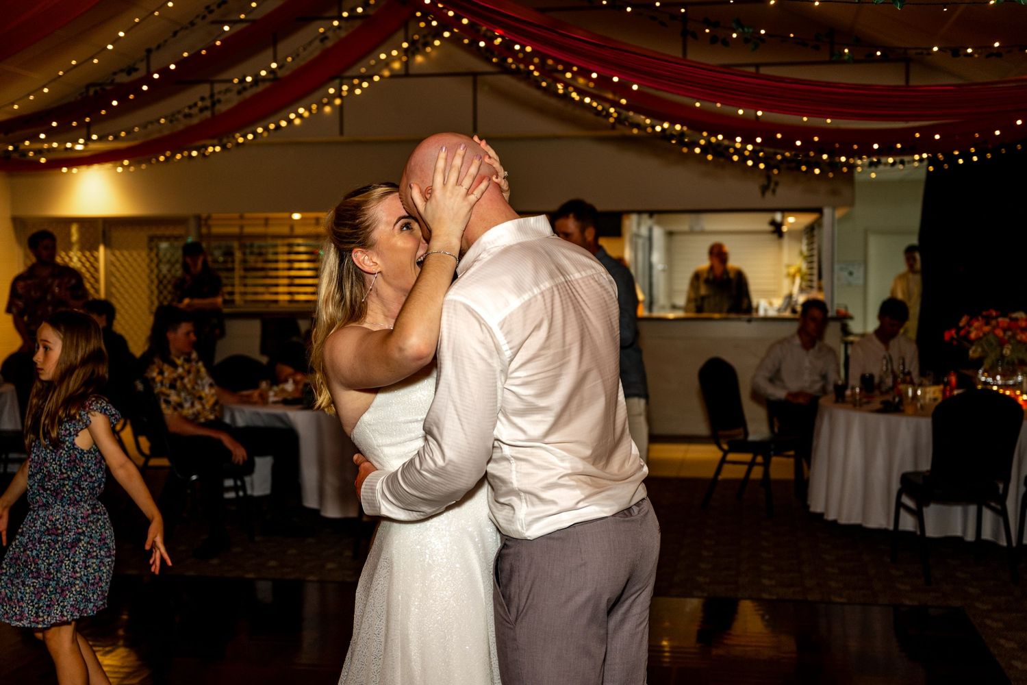 Newlyweds share a romantic kiss on the dance floor during their wedding reception celebration.
